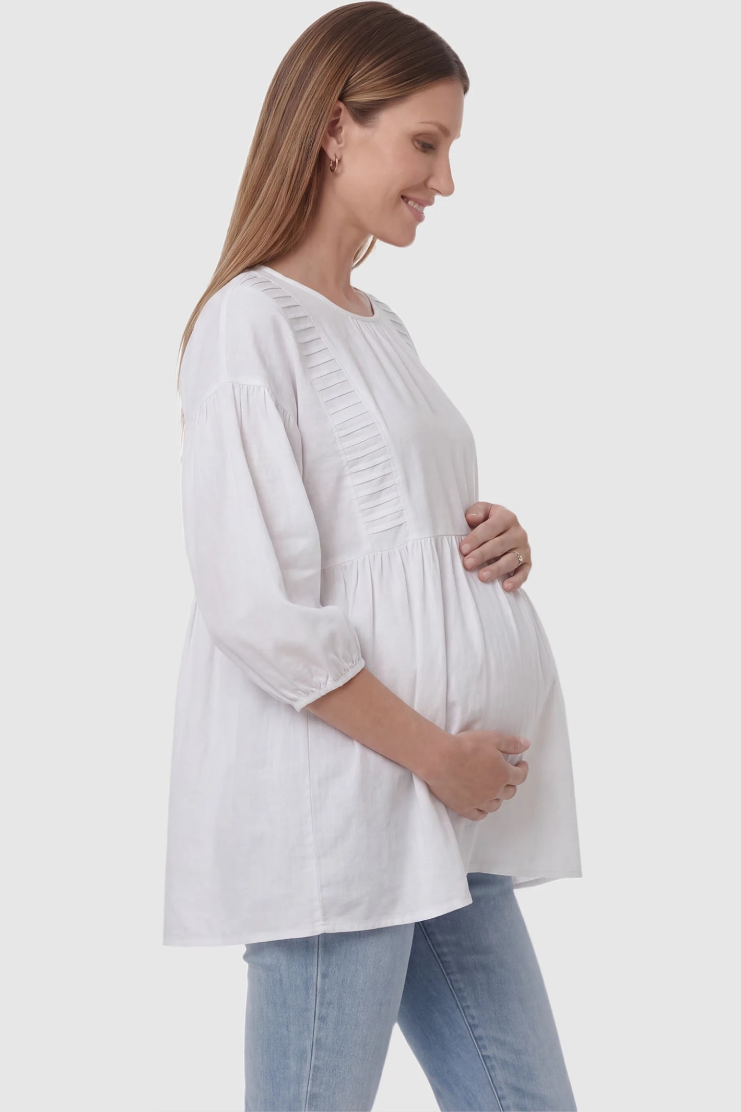 Peplum Round Neck Maternity Blouse Peplum round neck maternity blouse in white with flowy peplum and 3/4 sleeves, side view on pregnant model