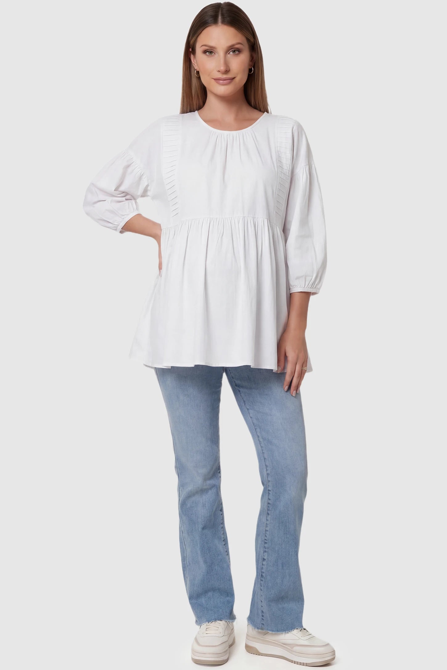 Peplum Round Neck Maternity Blouse Peplum round neck maternity blouse in white with flowy peplum and 3/4 sleeves, front view on pregnant model