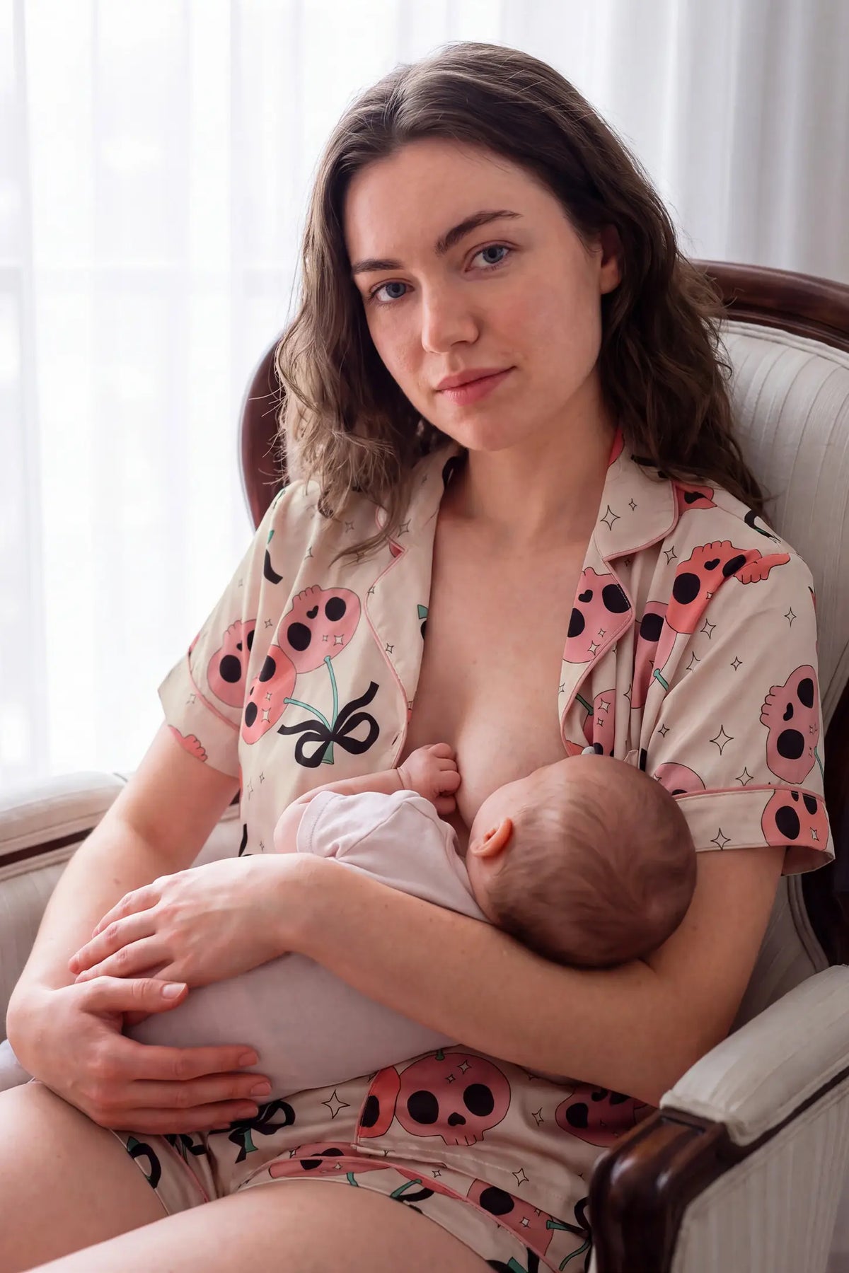 Pink Skull Cherry Button-Up Maternity Pajama Set Pink Skull Cherry Button-Up Maternity Pajama Set in Pink Skull featuring lightweight breathable fabric, flattering bump-accommodating fit, and relaxed shorts on a pregnant model, sofa lounging view.