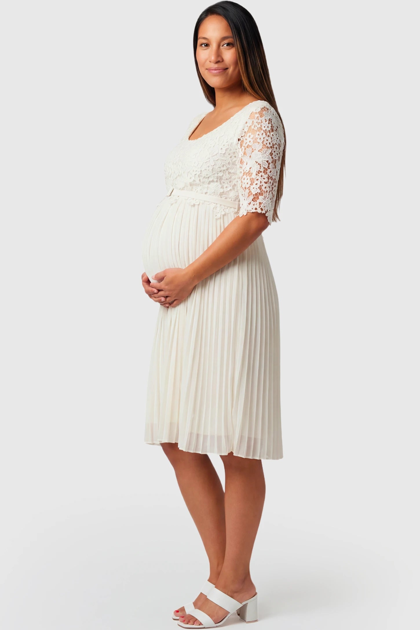 Pleated 3/4 Lace Sleeve Maternity Midi Dress in white featuring scoop neckline, lace sleeves, empire waist, and flowy pleated skirt on pregnant model.