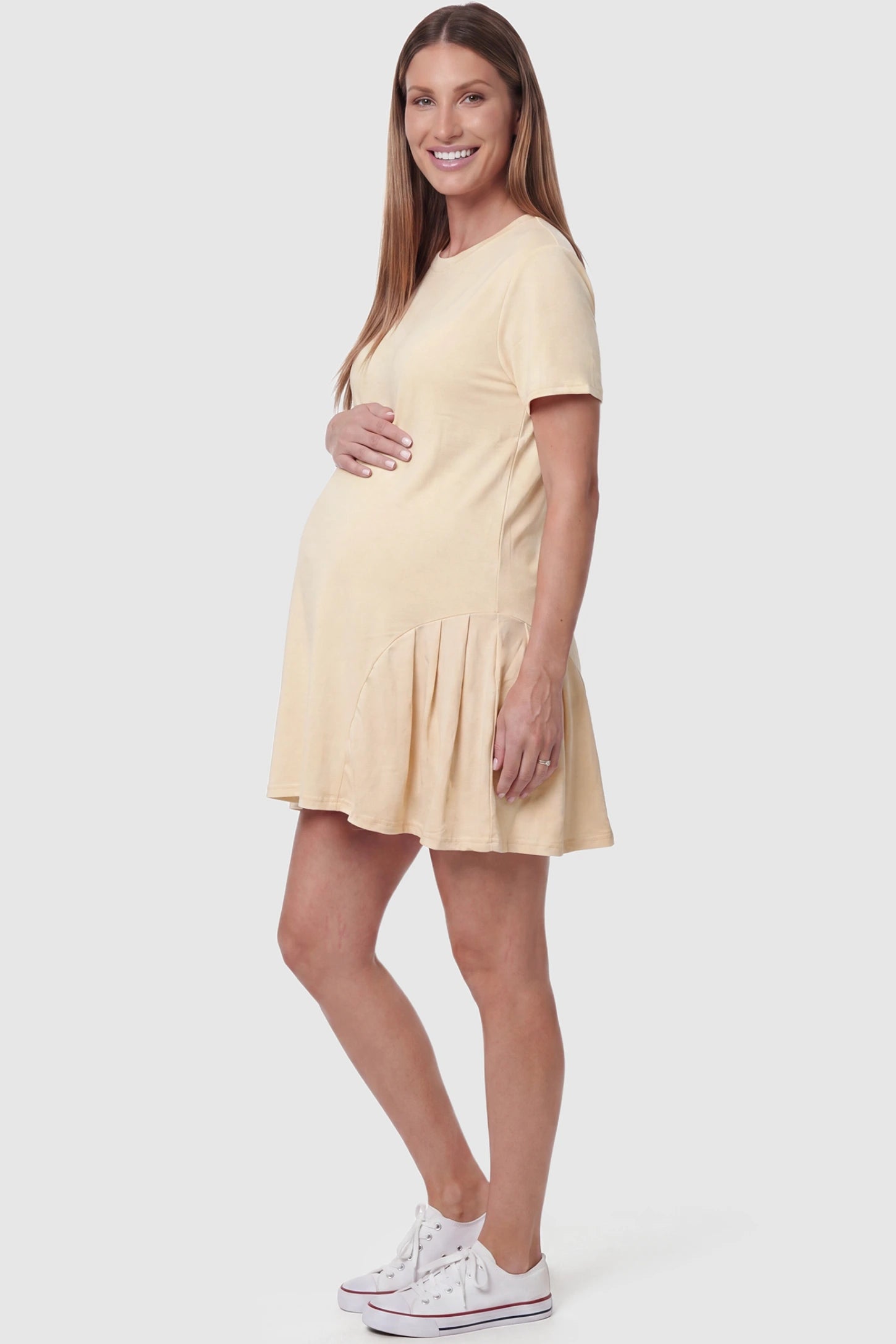 Pleated Hem A-line Maternity Short Dress Pleated hem A-line maternity short dress in beige with short sleeves, side view on pregnant model