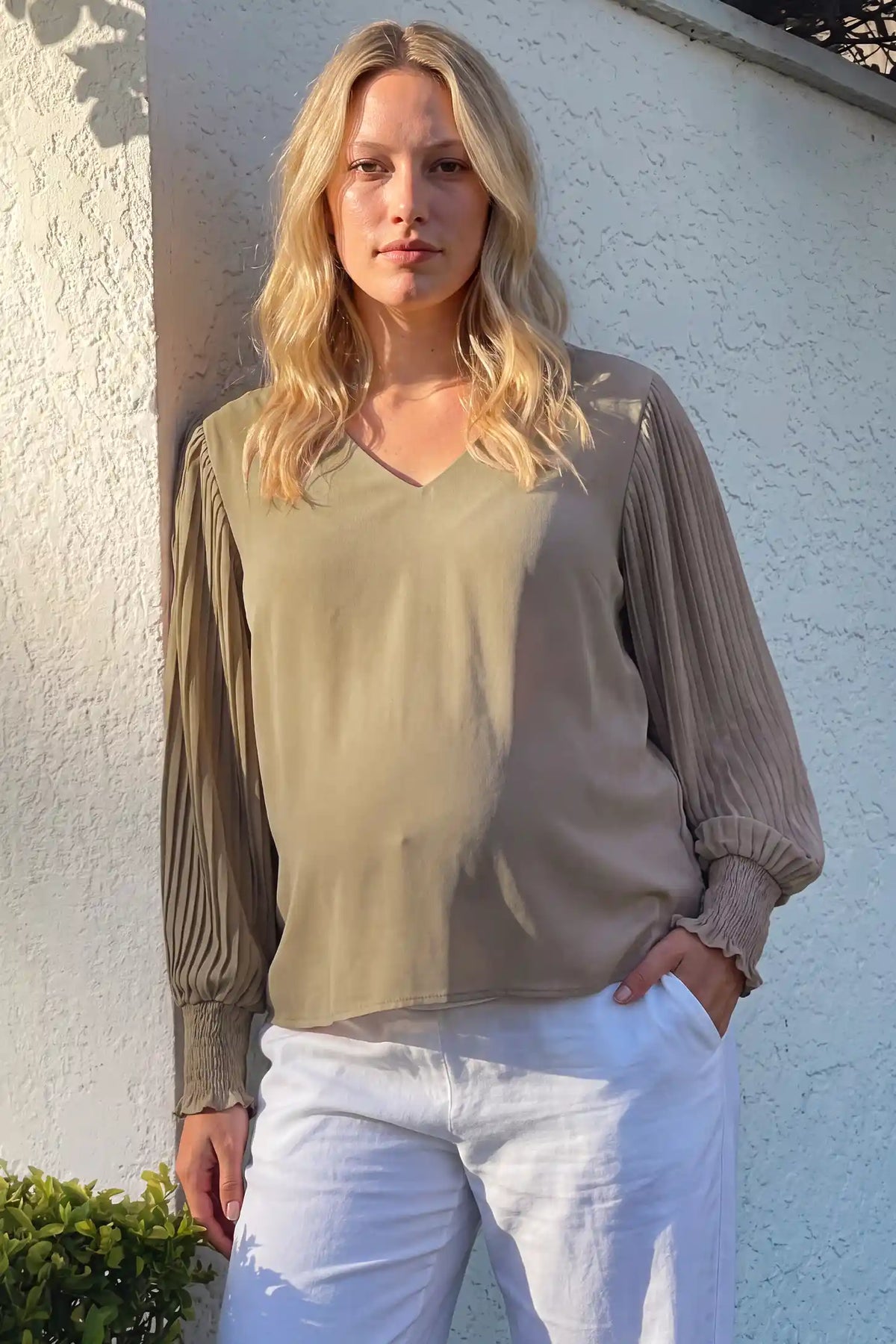 Pleated Sleeve V-Neck Maternity Blouse Pleated Sleeve V-Neck Maternity Blouse in Khaki featuring a classic V-neckline and elegant long sleeves on a pregnant model paired with white pants, outdoor lifestyle front view.