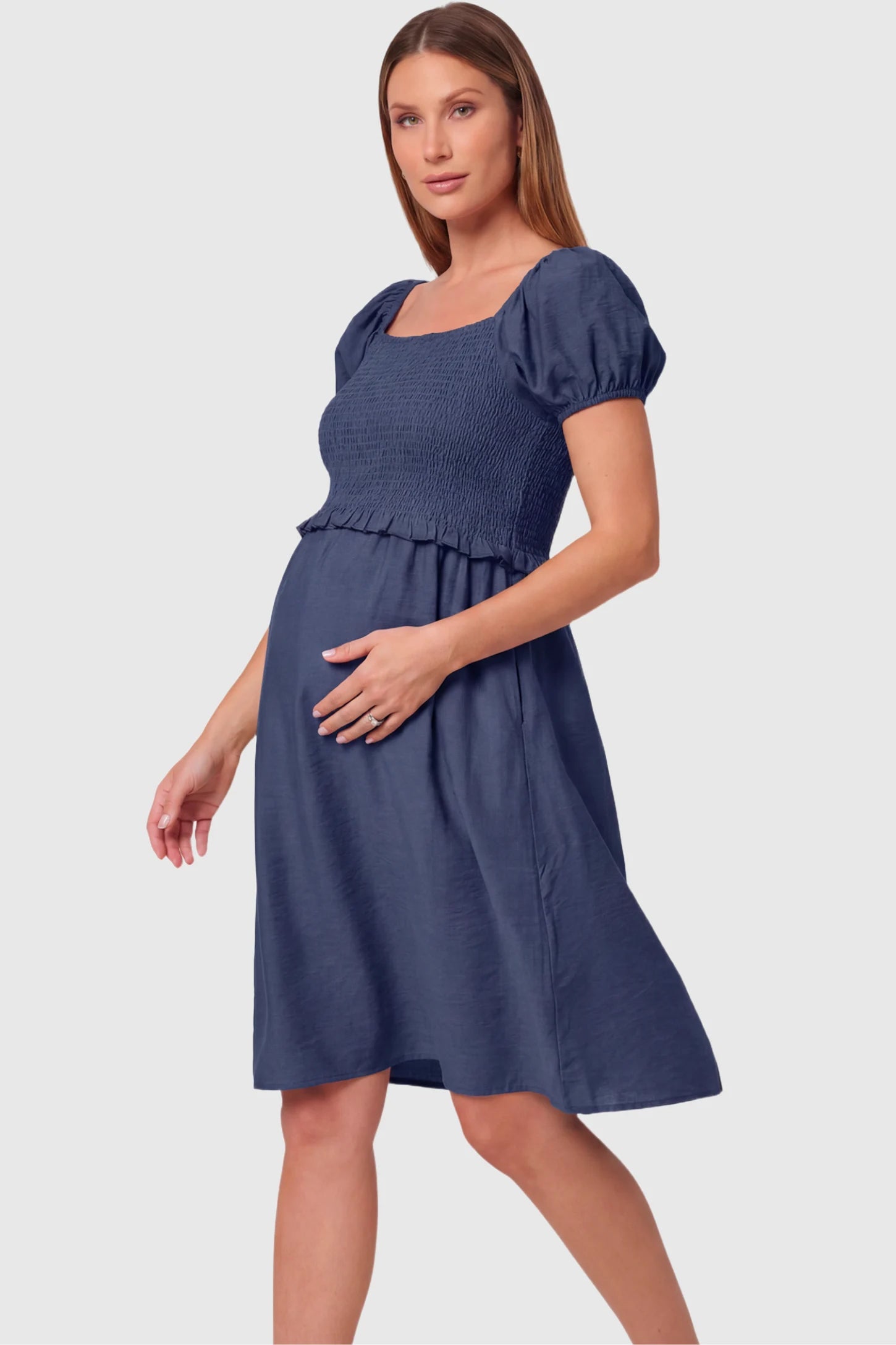 Short Puff Sleeve Empire Waist Maternity & Nursing Midi Dress Short Puff Sleeve Empire Waist Maternity & Nursing Midi Dress in navy blue featuring a square neck, smocked bodice, and A-line silhouette on a pregnant model.