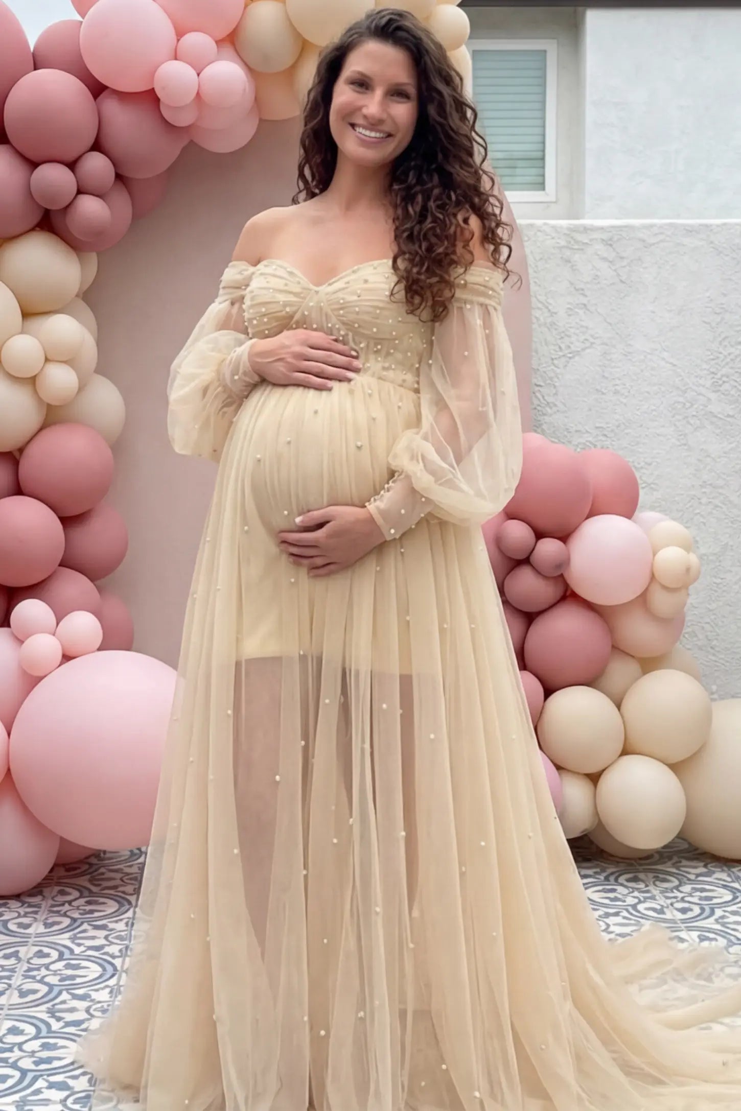 Off-Shoulder Empire Waist Maternity Gown Off-Shoulder Empire Waist Maternity Gown in camel featuring a sweetheart neckline and flowy A-line silhouette on a pregnant woman, front view.