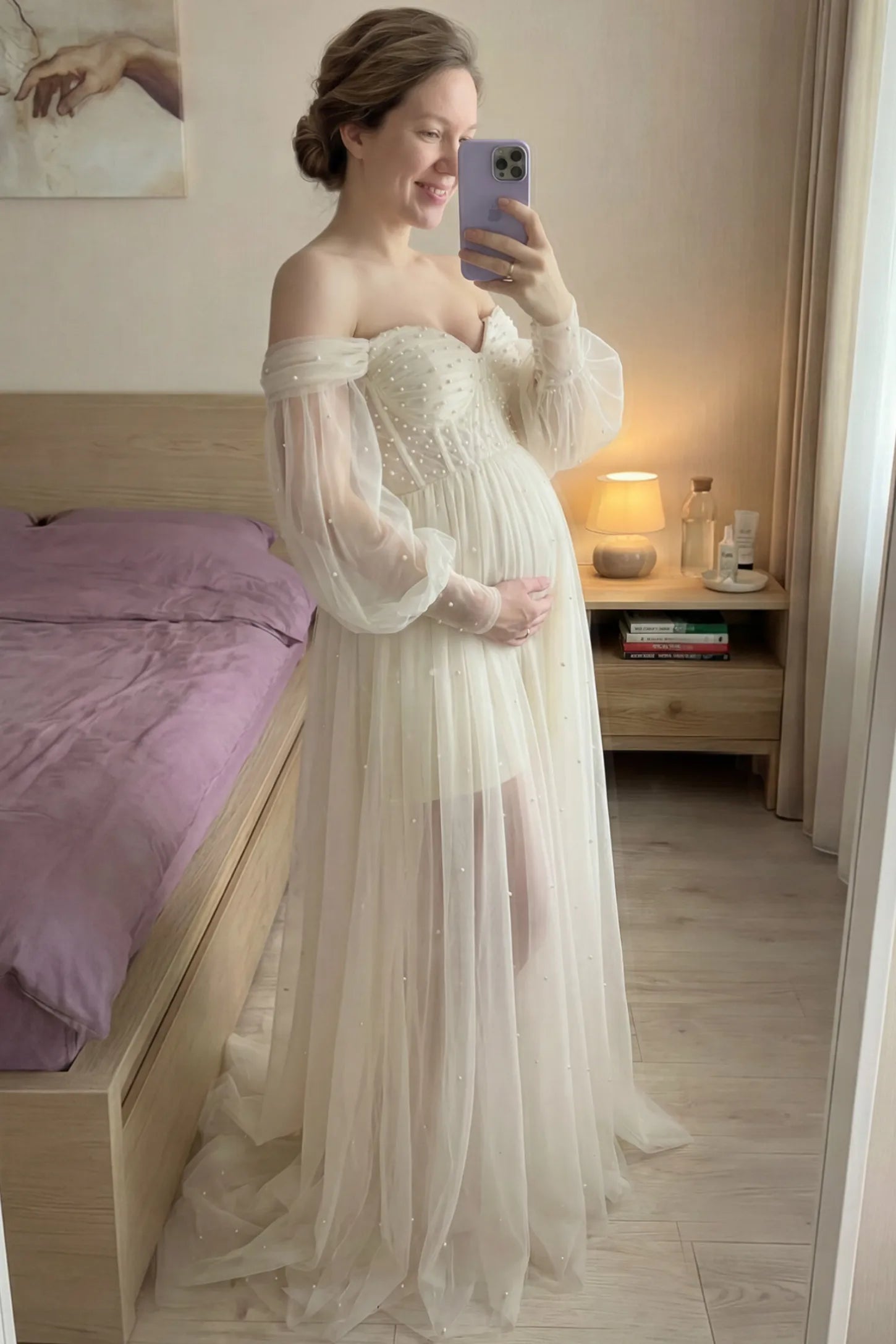 Off-Shoulder Empire Waist Maternity Gown Off-Shoulder Empire Waist Maternity Gown in ivory featuring a sweetheart neckline and flowy A-line silhouette on a pregnant woman.
