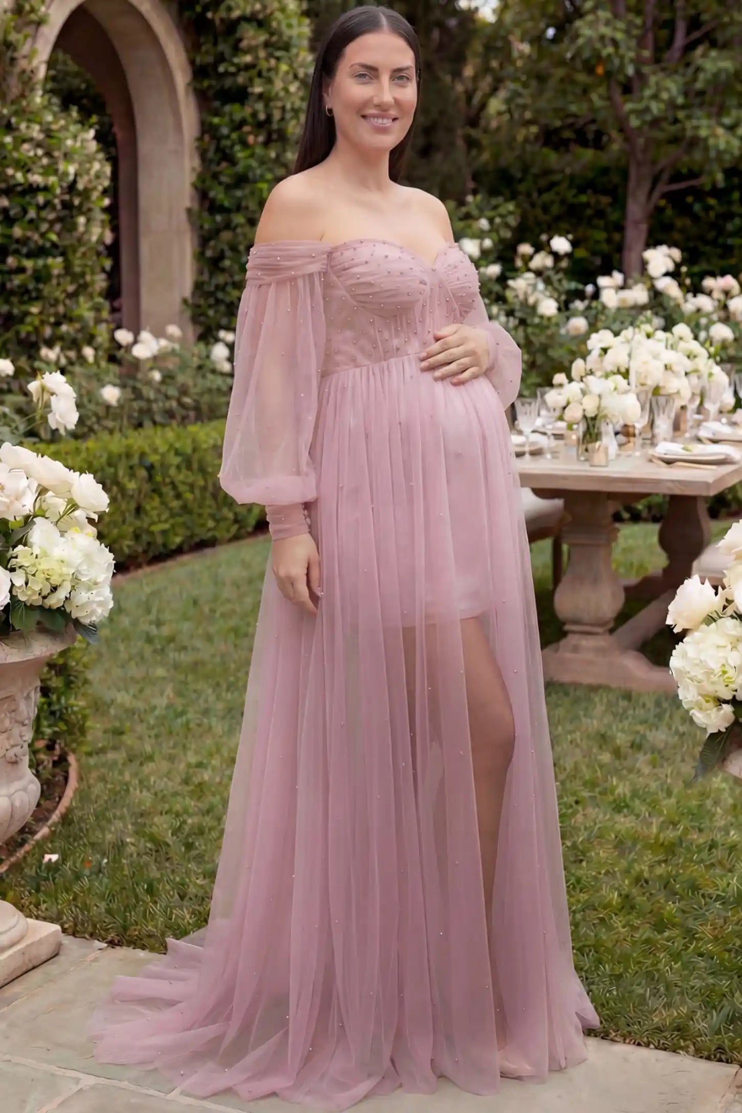 Off-Shoulder Empire Waist Maternity Gown Off-Shoulder Empire Waist Maternity Gown in pink featuring a sweetheart neckline and flowy A-line silhouette on a plus size pregnant model, front view.