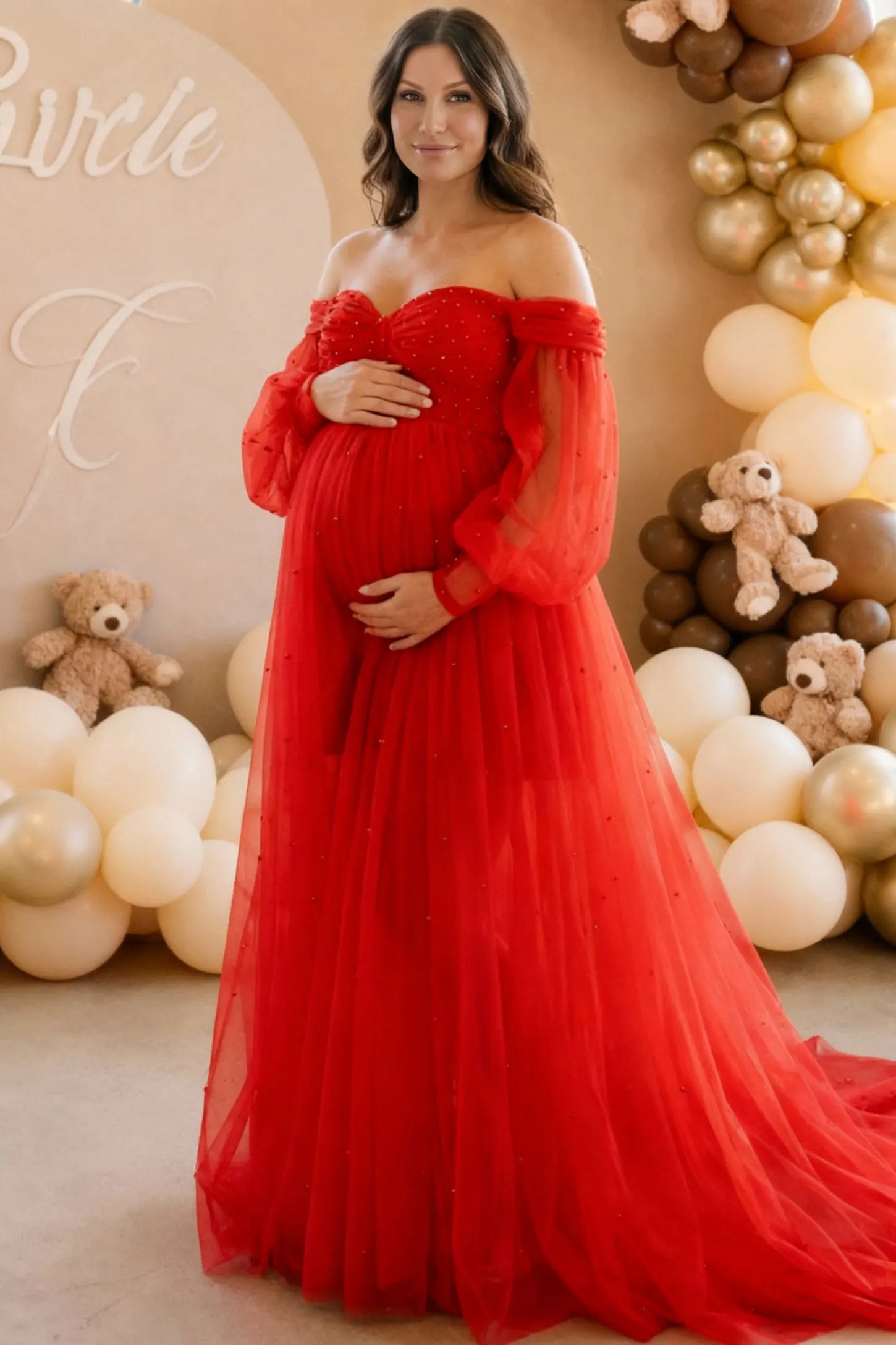 Off-Shoulder Empire Waist Maternity Gown Off-Shoulder Empire Waist Maternity Gown in red featuring a sweetheart neckline and flowy A-line silhouette on a pregnant woman during indoor photoshoot.