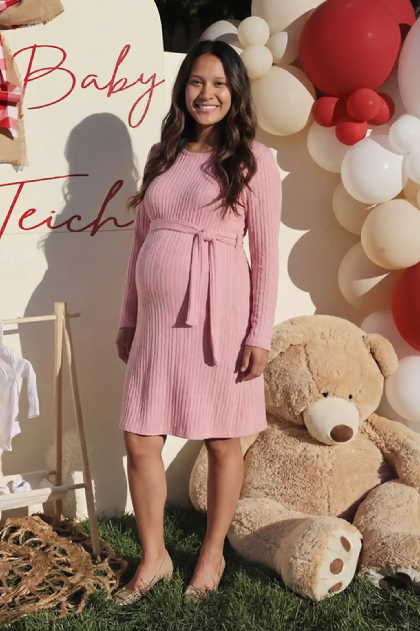 Ribbed Knit Long Sleeve Maternity Short Dress in pink featuring a ribbed texture and adjustable tie waist on a pregnant model.