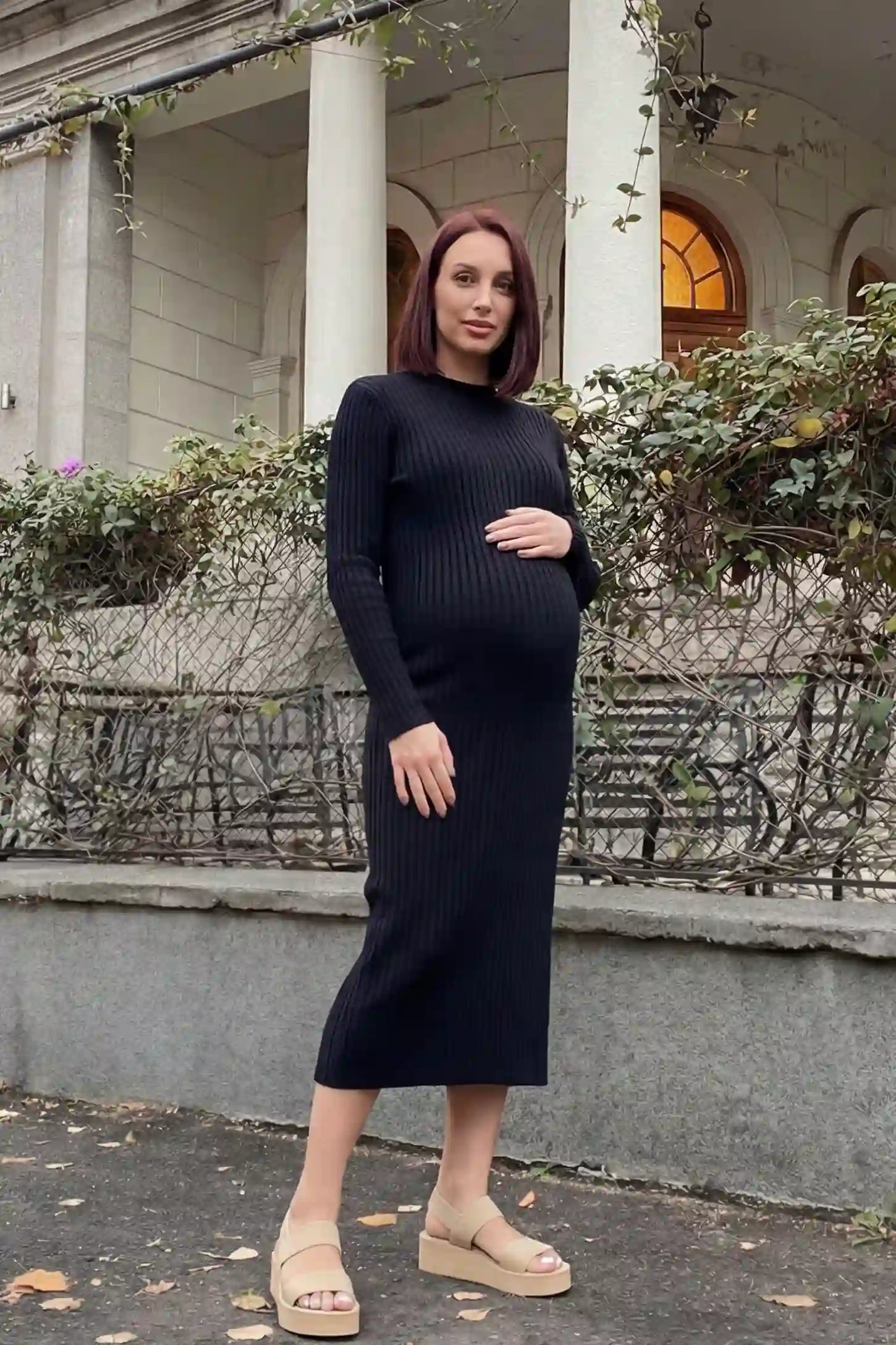 Ribbed knit long sleeve maternity midi dress in black with smooth stretch ribbed knit fabric, front view on pregnant model