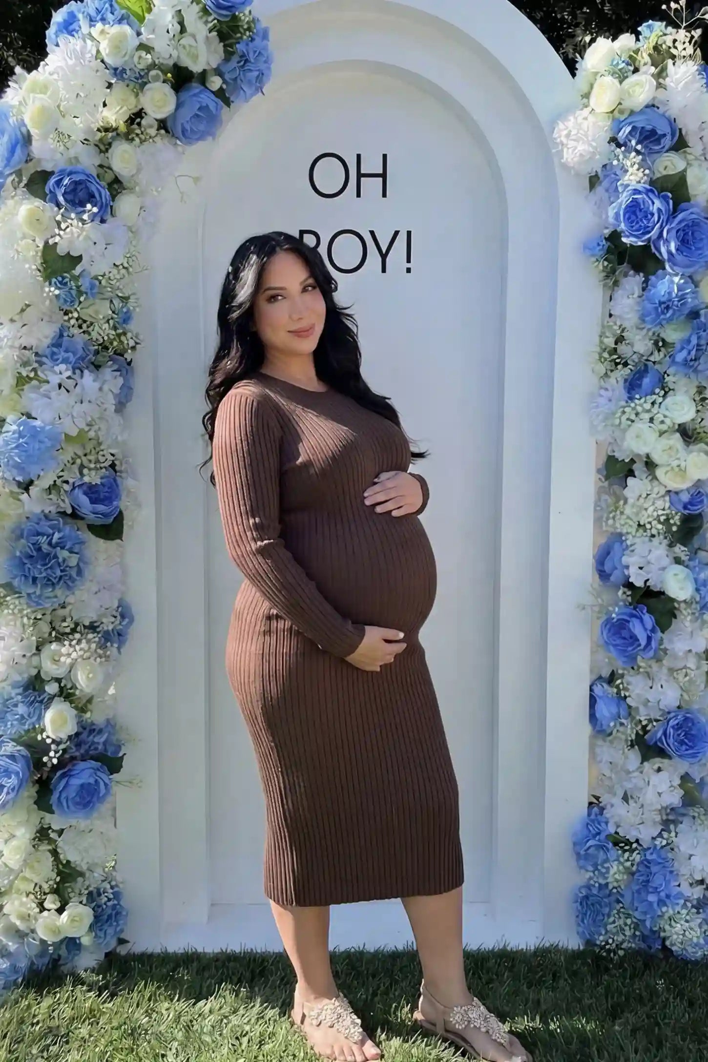 Ribbed Knit Long Sleeve Maternity Midi Dress Ribbed knit long sleeve maternity midi dress in brown with smooth stretch ribbed knit fabric, side view on pregnant model