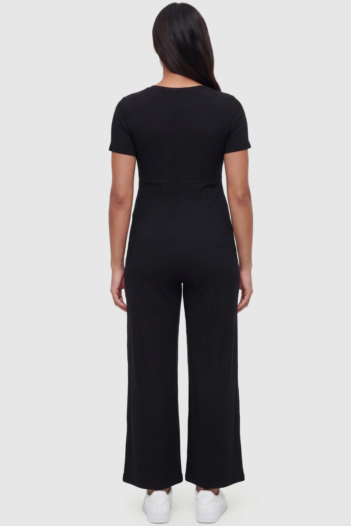 Round Neck Paperbag Waist Maternity Jumpsuit Round Neck Paperbag Waist Maternity Jumpsuit in Black featuring a ribbed empire on a pregnant model, back view.