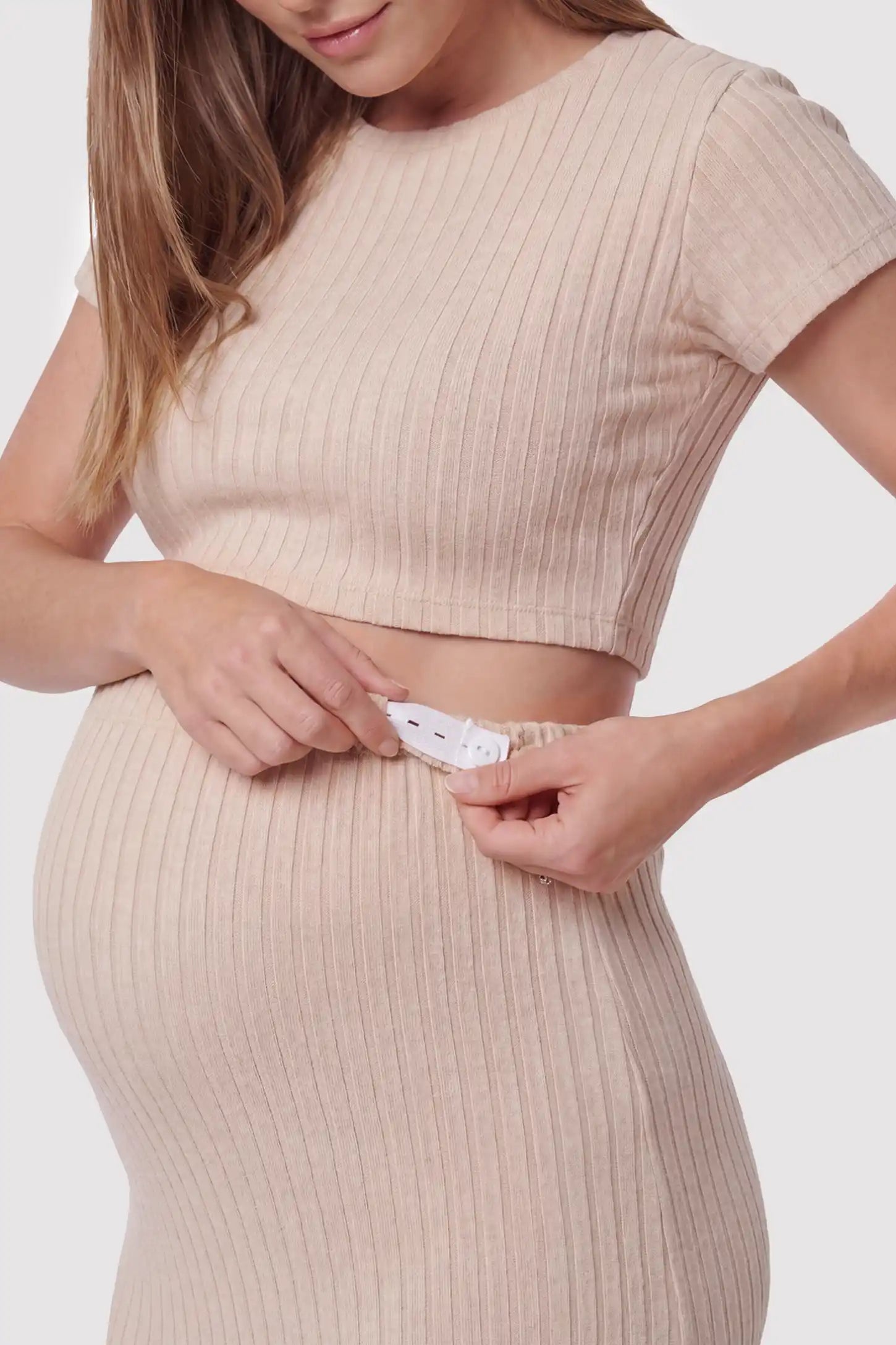 Ribbed Bodycon Crop Top & Skirt Maternity Set Ribbed Bodycon Crop Top & Skirt Maternity Set in beige featuring adjustable waist band, fitted ribbed knit silhouette on a pregnant model, front view.