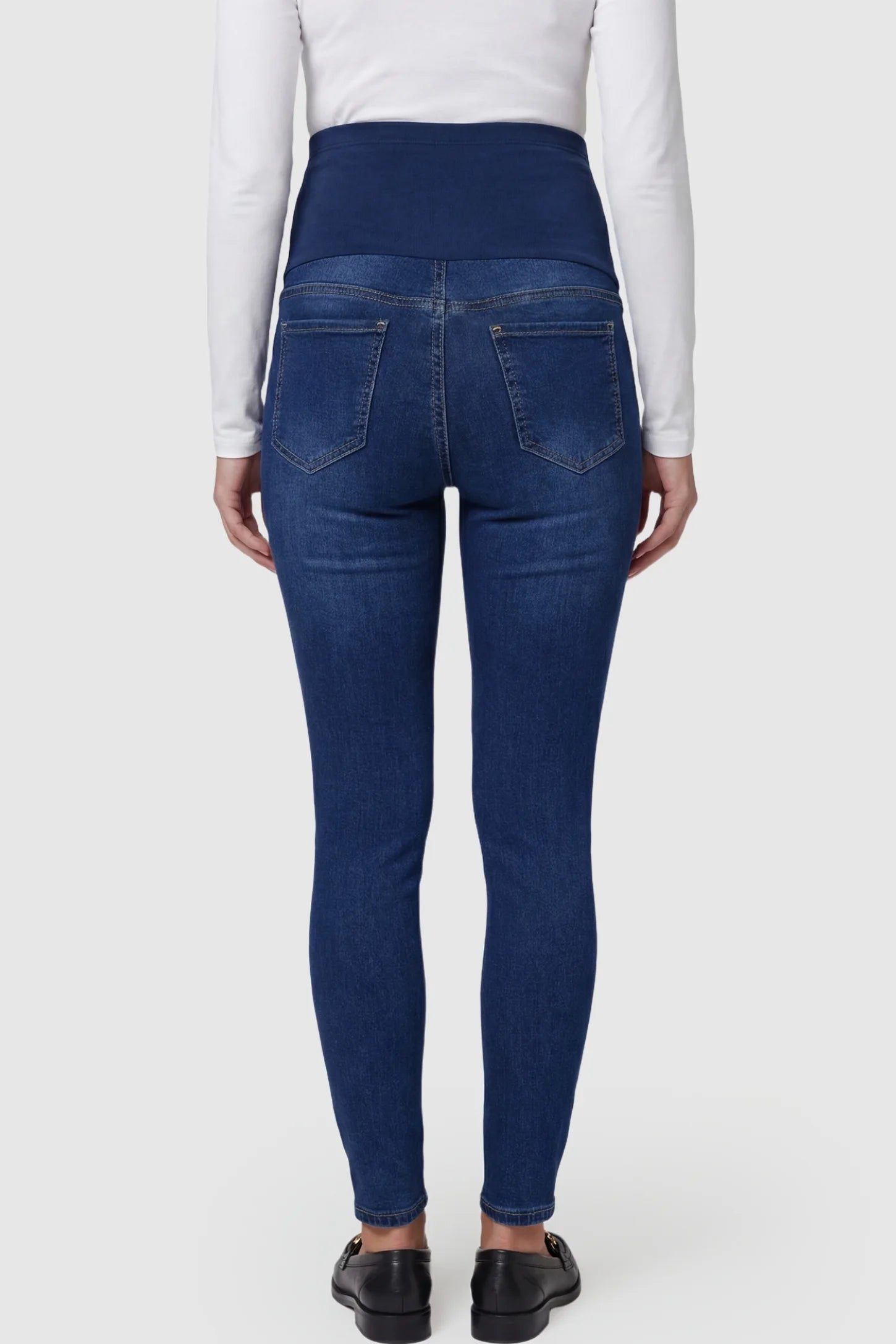 Distressed Ripped High-Waist Skinny Maternity Jeans Distressed ripped high-waist skinny maternity jeans in dark blue with rear pocket detail, back view on pregnant model