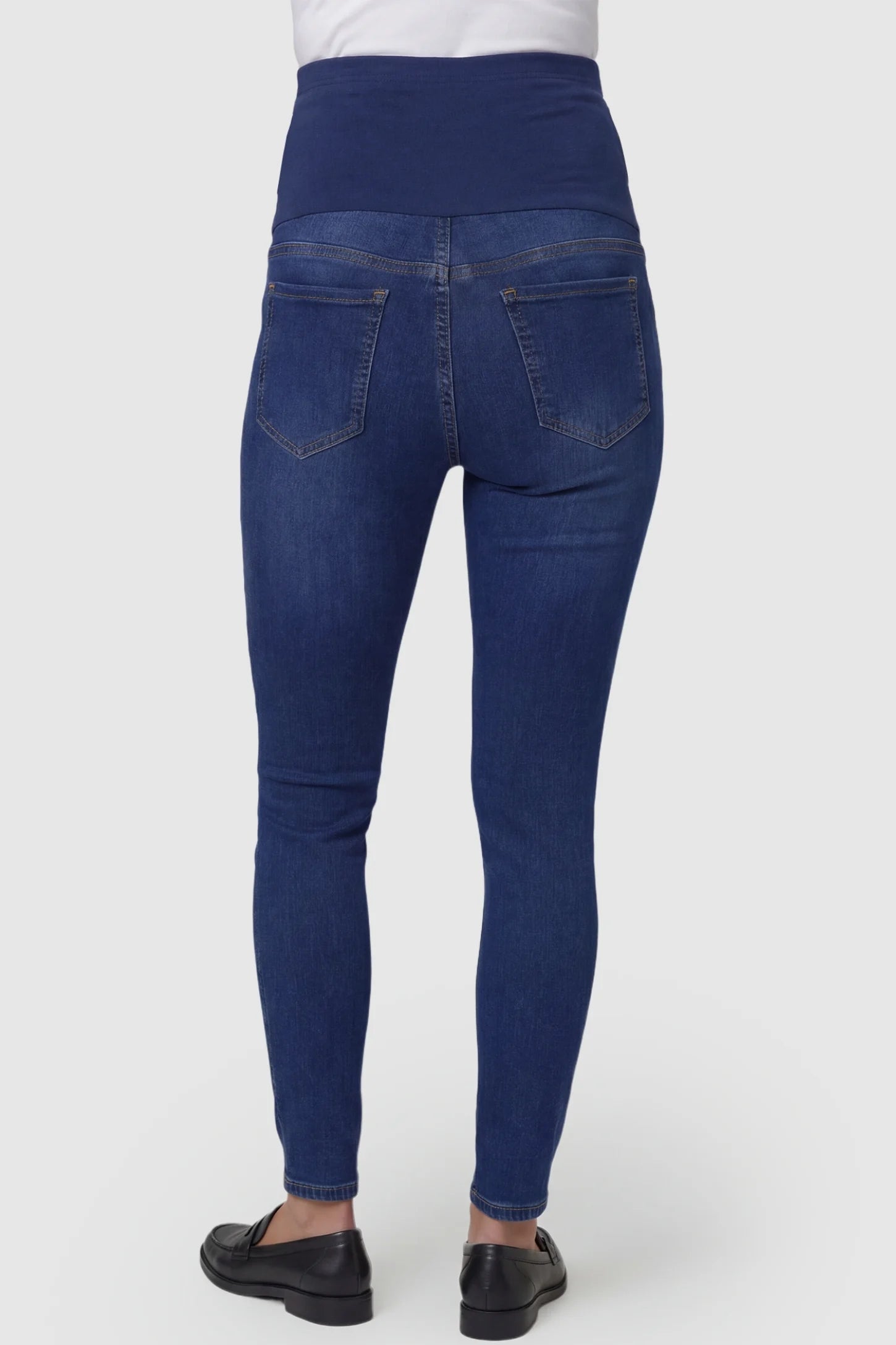 Distressed Ripped High-Waist Skinny Maternity Jeans Distressed ripped high-waist skinny maternity jeans in dark blue with rear pocket detail, back view on pregnant model