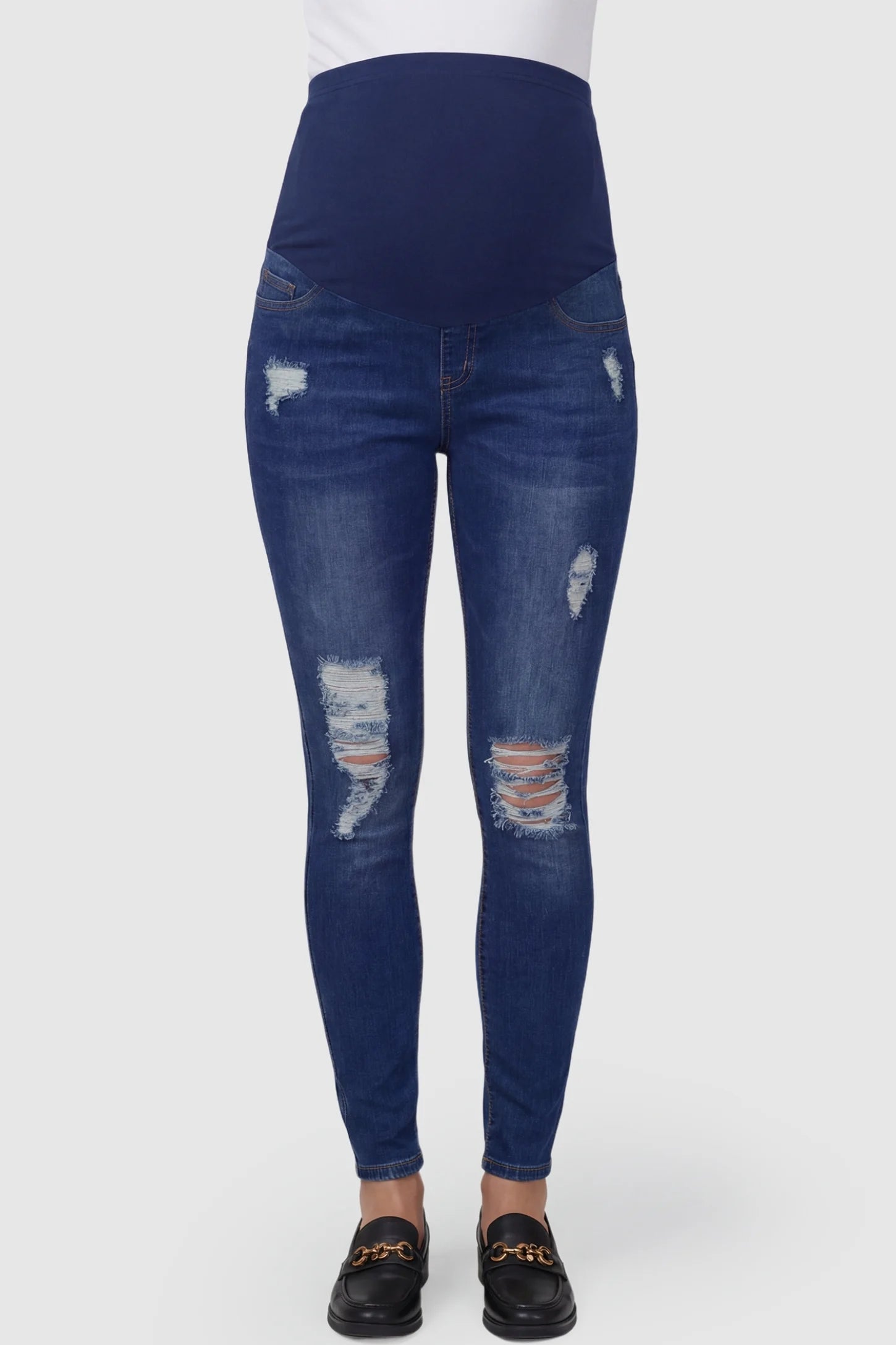 Distressed ripped high-waist skinny maternity jeans in dark blue with ripped design, front view on pregnant model
