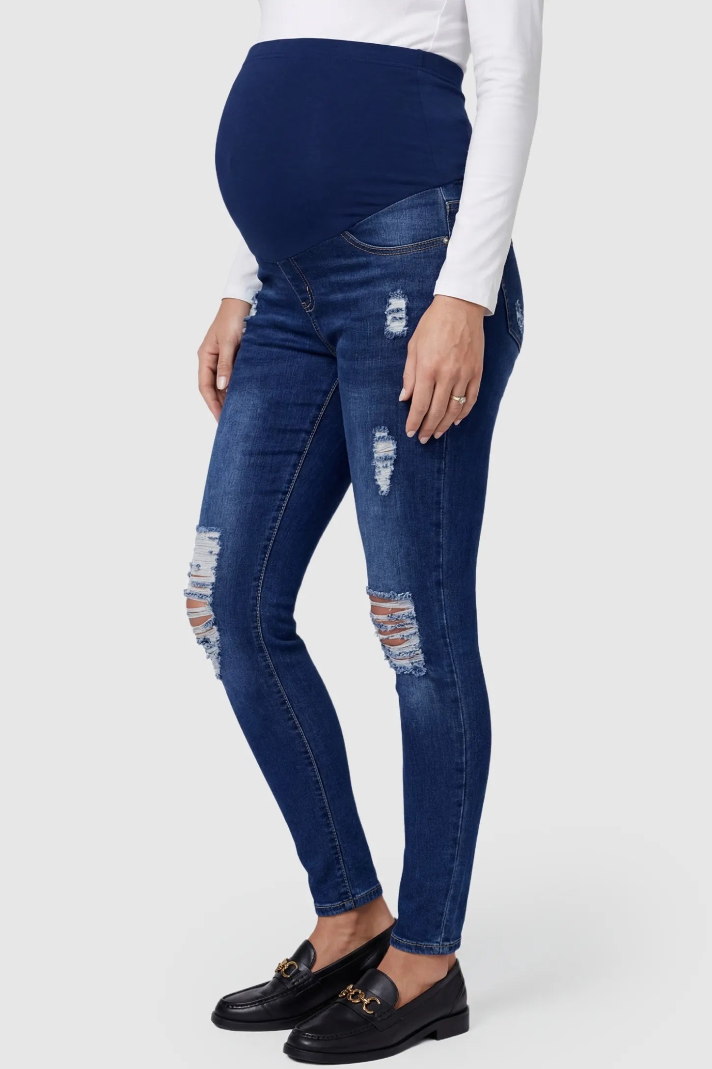 Distressed Ripped High-Waist Skinny Maternity Jeans Distressed ripped high-waist skinny maternity jeans in dark blue with skinny fit, side view on pregnant model