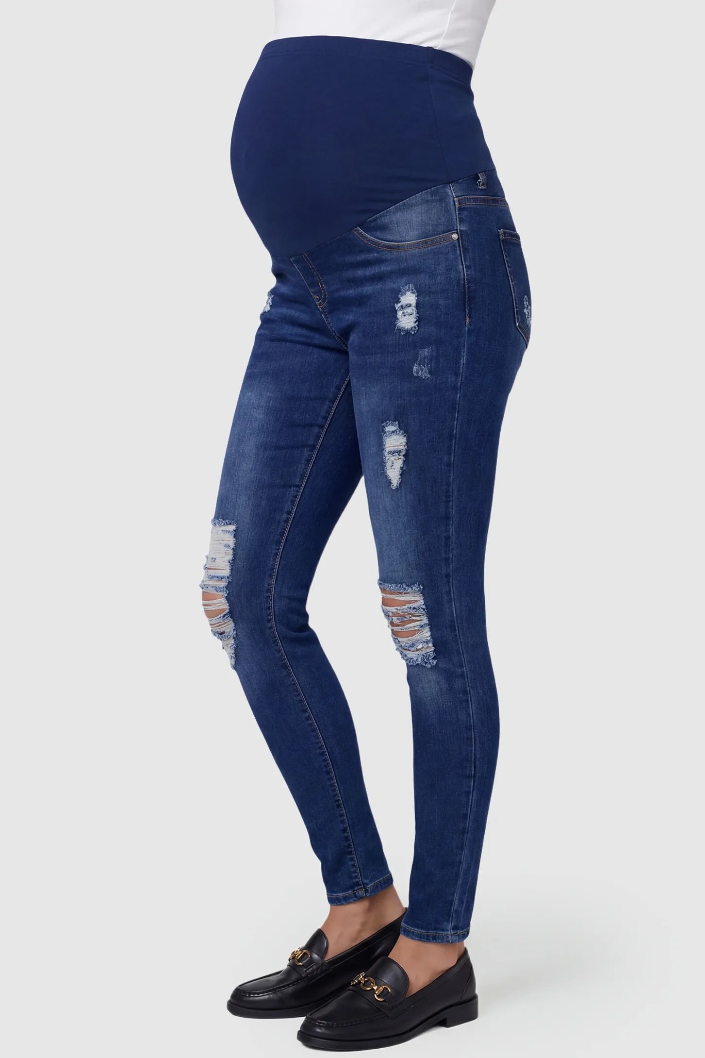 Distressed Ripped High-Waist Skinny Maternity Jeans Distressed ripped high-waist skinny maternity jeans in dark blue with skinny fit, side view on pregnant model