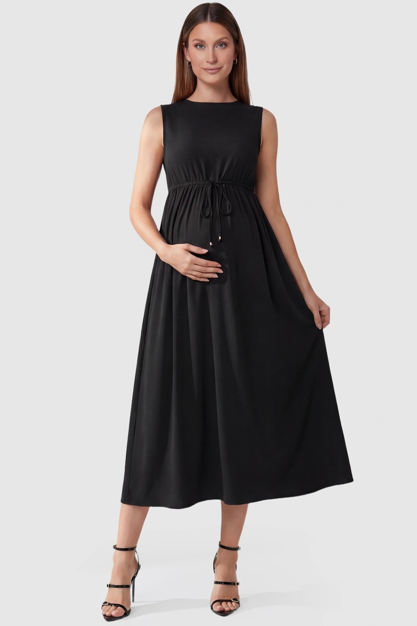 Drawstring Waist Sleeveless Full Skirt Maternity Skater Dress Drawstring Waist Sleeveless Maternity Skater Dress in Black featuring a flexible adjustable waist on a pregnant model.
