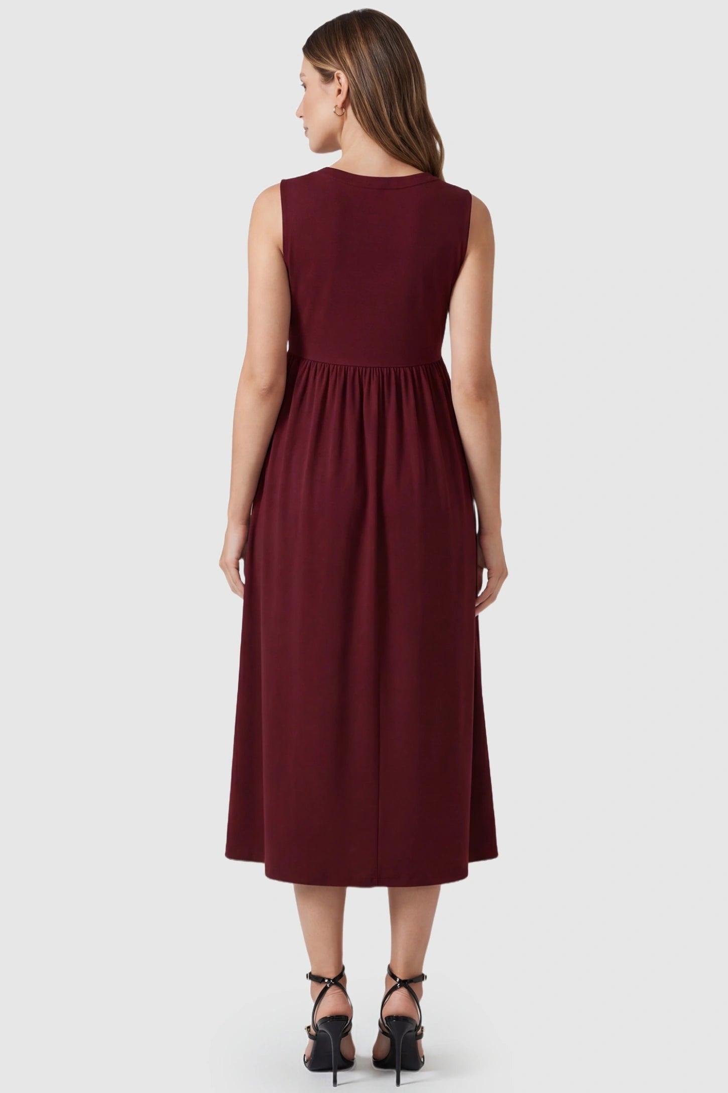 Drawstring Waist Sleeveless Full Skirt Maternity Skater Dress Drawstring Waist Sleeveless Maternity Skater Dress in Burgundy featuring a high-back full skirt on a postpartum model.