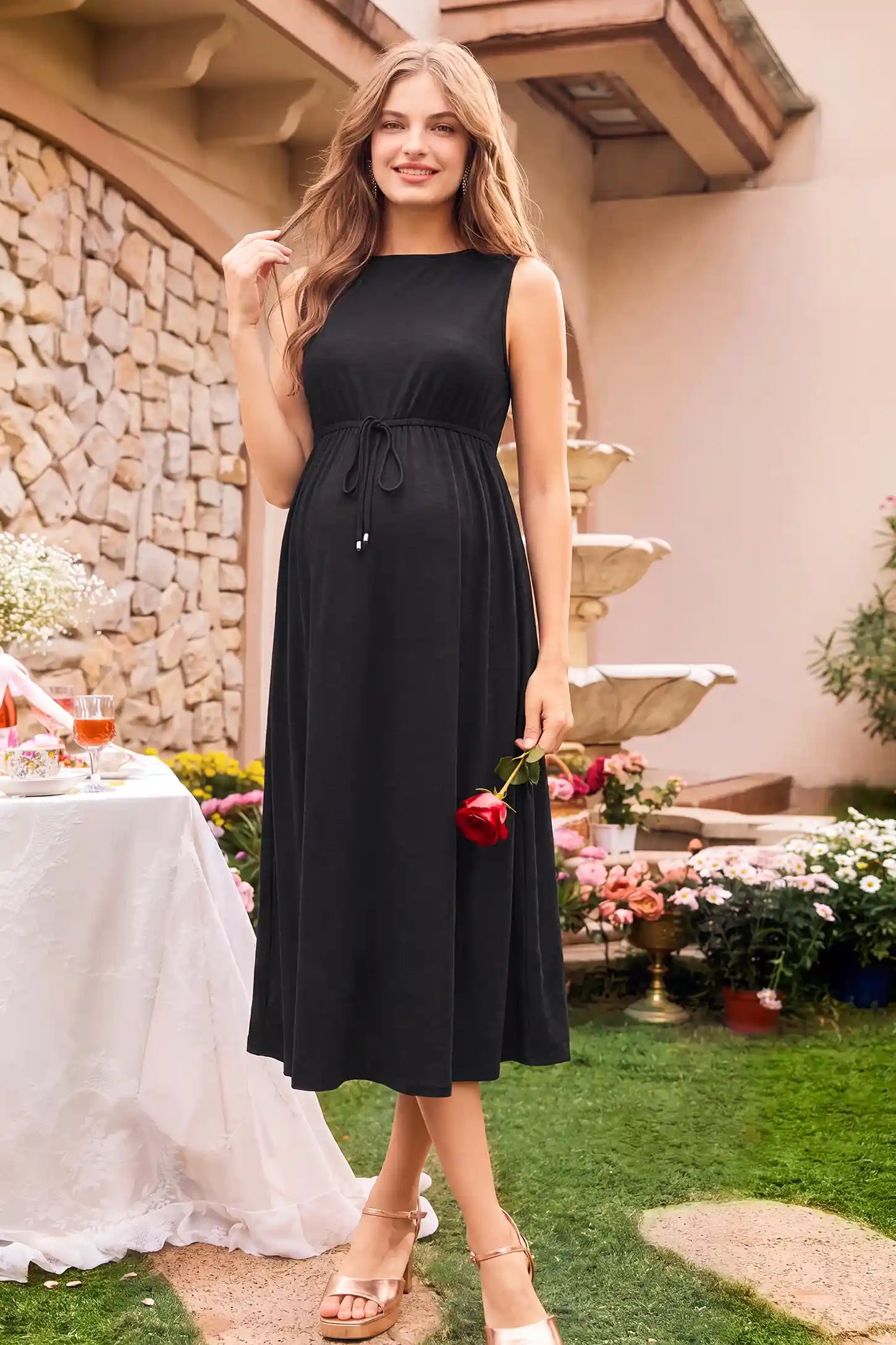 Drawstring Waist Sleeveless Full Skirt Maternity Skater Dress Drawstring Waist Sleeveless Maternity Skater Dress in black featuring a side profile bump view on a pregnant model outdoors.