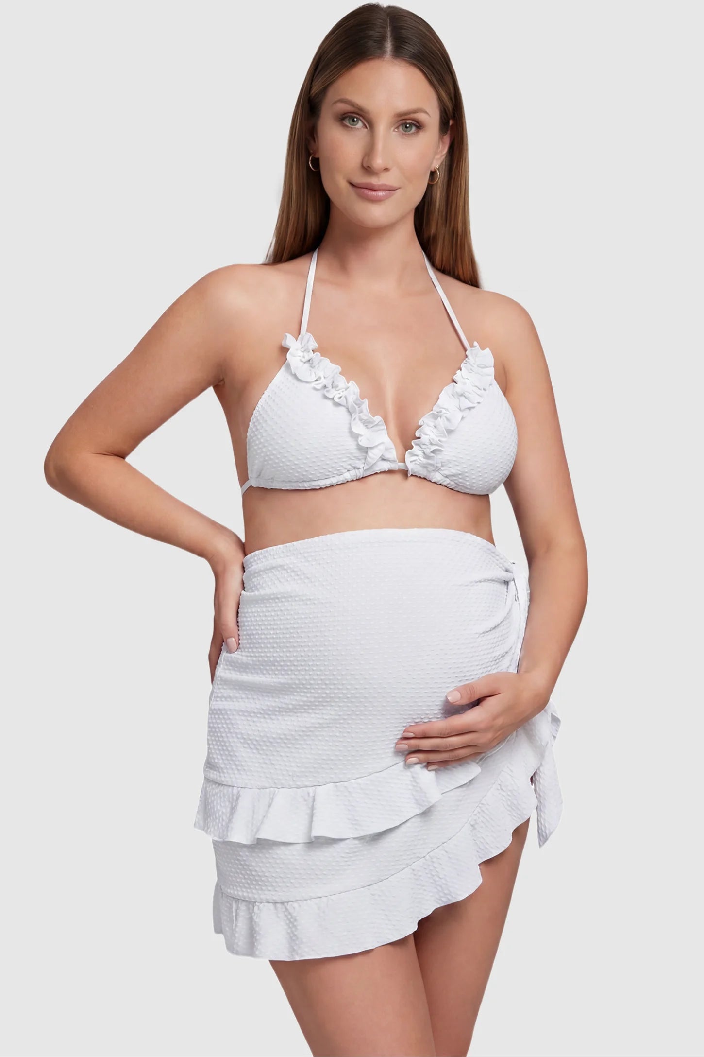 Ruffled trim halter maternity bikini set in white with halter neckline and ruffle detail, front view on pregnant model