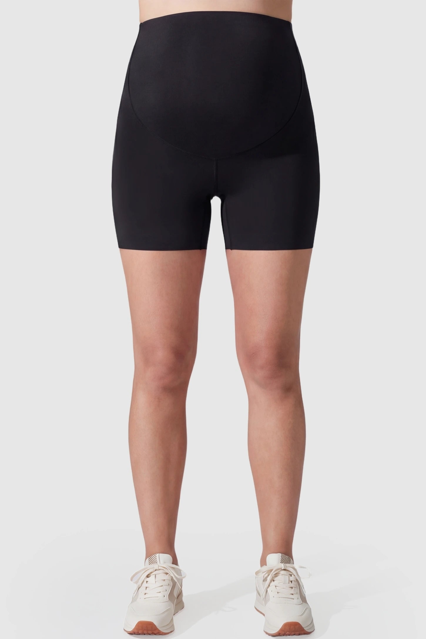 Seamless high-waist slim-fit maternity shorts in black with tummy support, front view on pregnant model