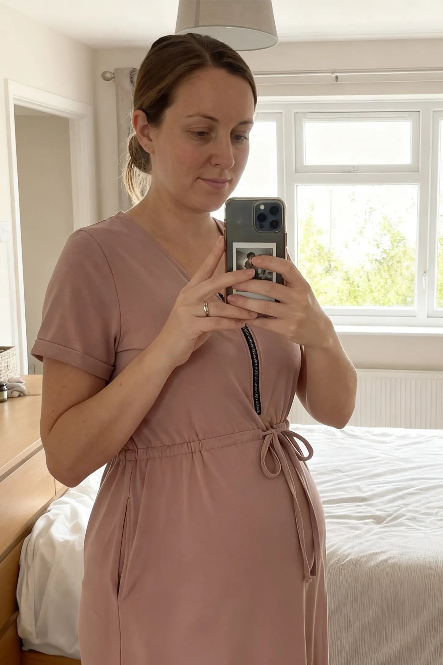 Scoop Neck Short Sleeve Maternity & Nursing Dress Scoop neck short sleeve maternity and nursing dress in rose gold featuring front zipper closure and tie-waist in front view on a UGC model