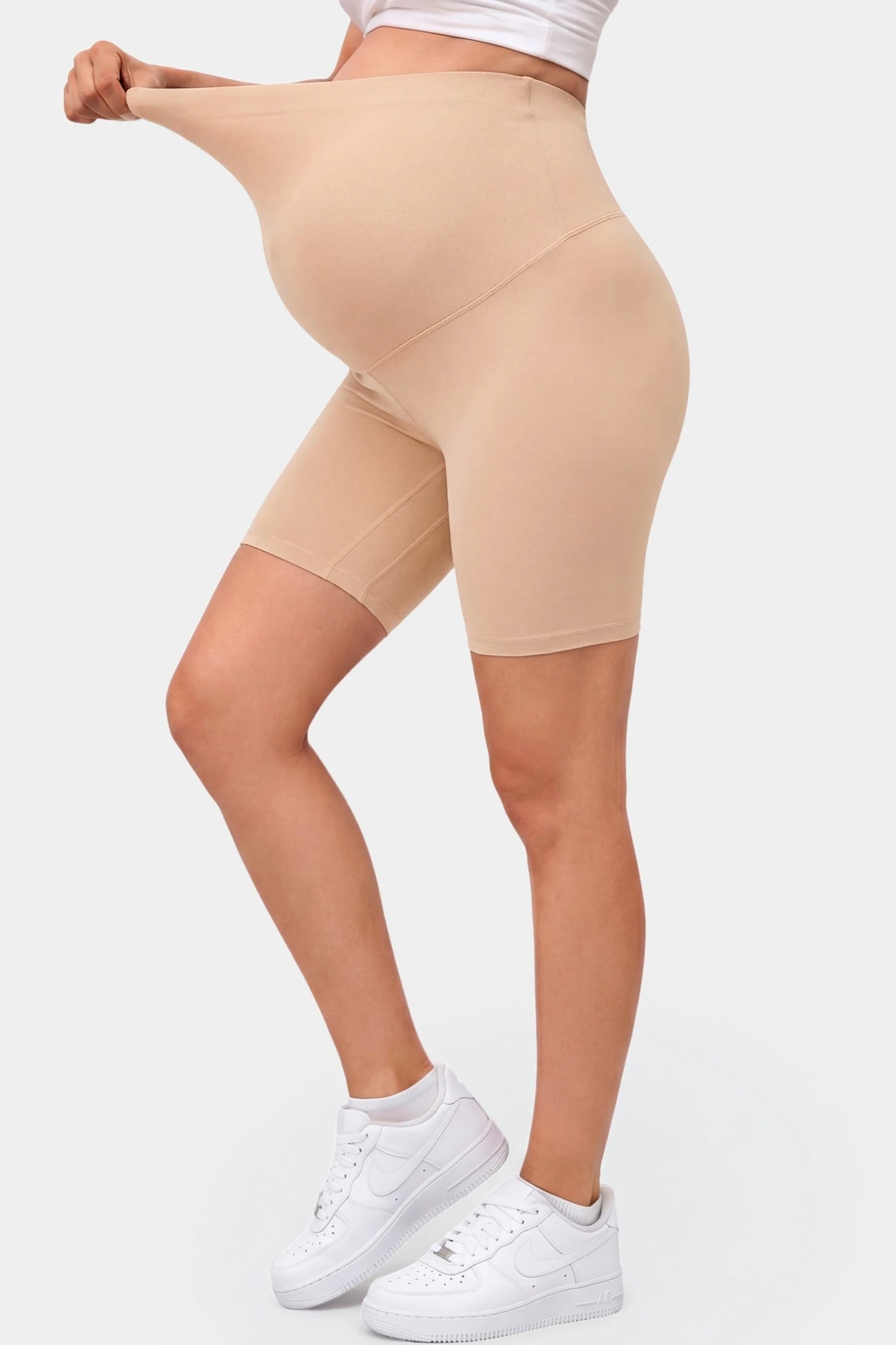 Seamless Belly Support Mid-Thigh Shaping Maternity Shorts Seamless belly support mid-thigh shaping maternity shorts in beige with flexible compression, side view on pregnant model