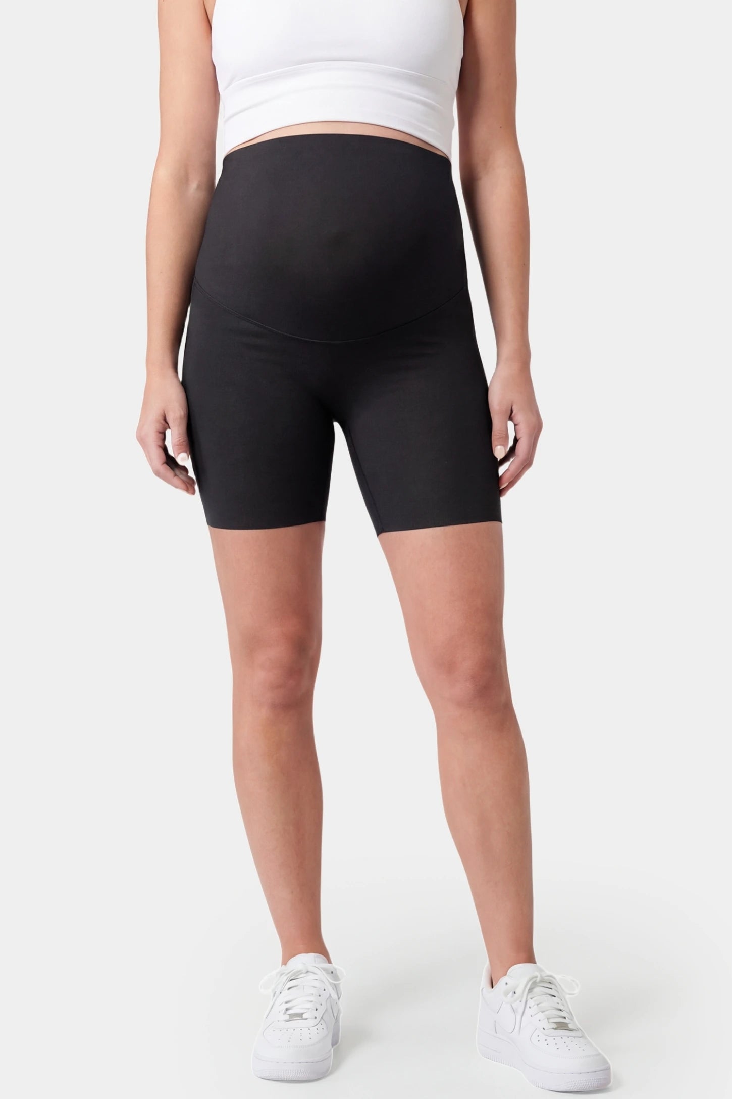 Seamless Belly Support Mid-Thigh Shaping Maternity Shorts Seamless belly support mid-thigh shaping maternity shorts in black with high-waist support, front view on pregnant model