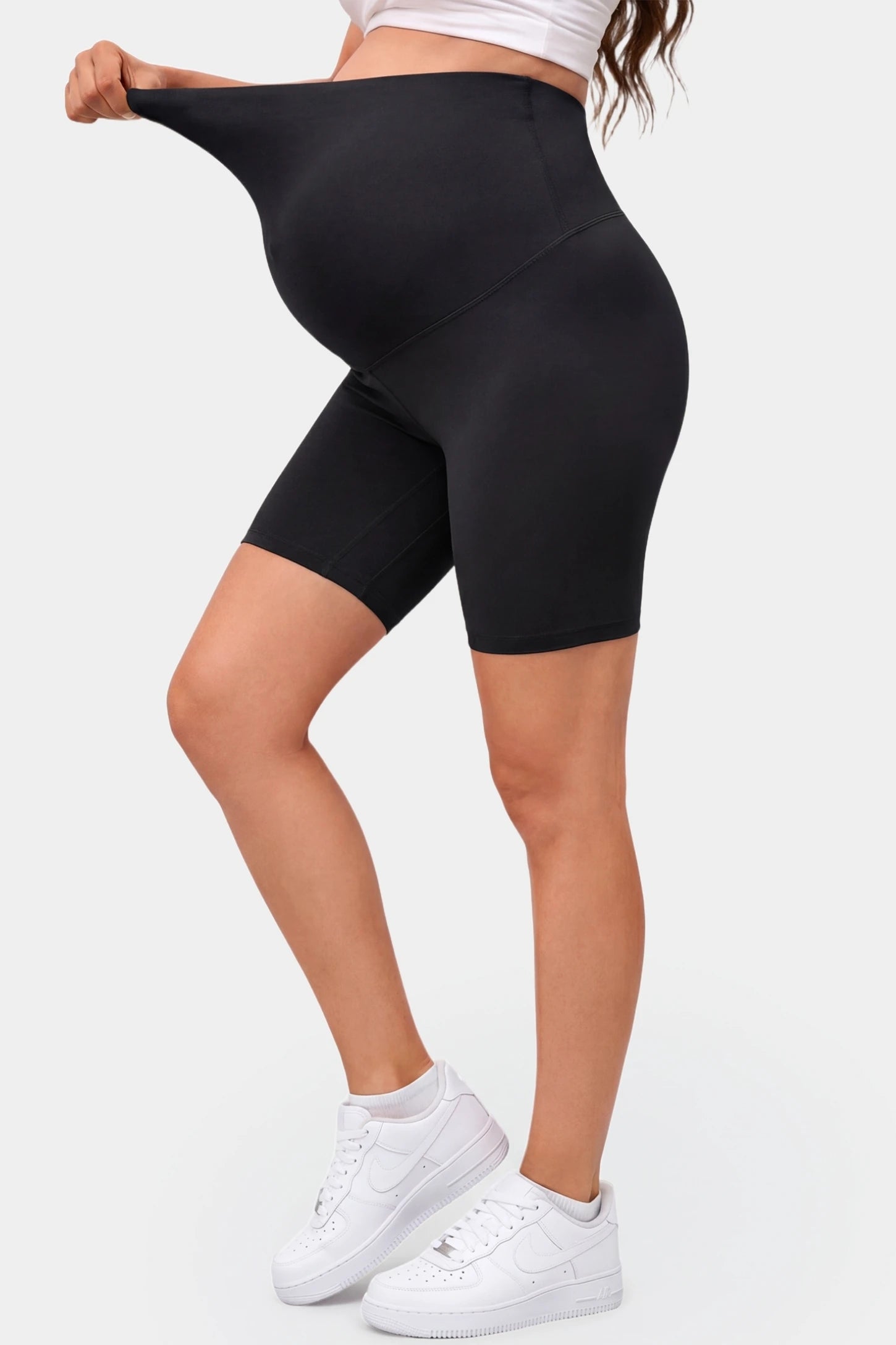 Seamless Belly Support Mid-Thigh Shaping Maternity Shorts Seamless belly support mid-thigh shaping maternity shorts in black with flexible compression, side view on pregnant model