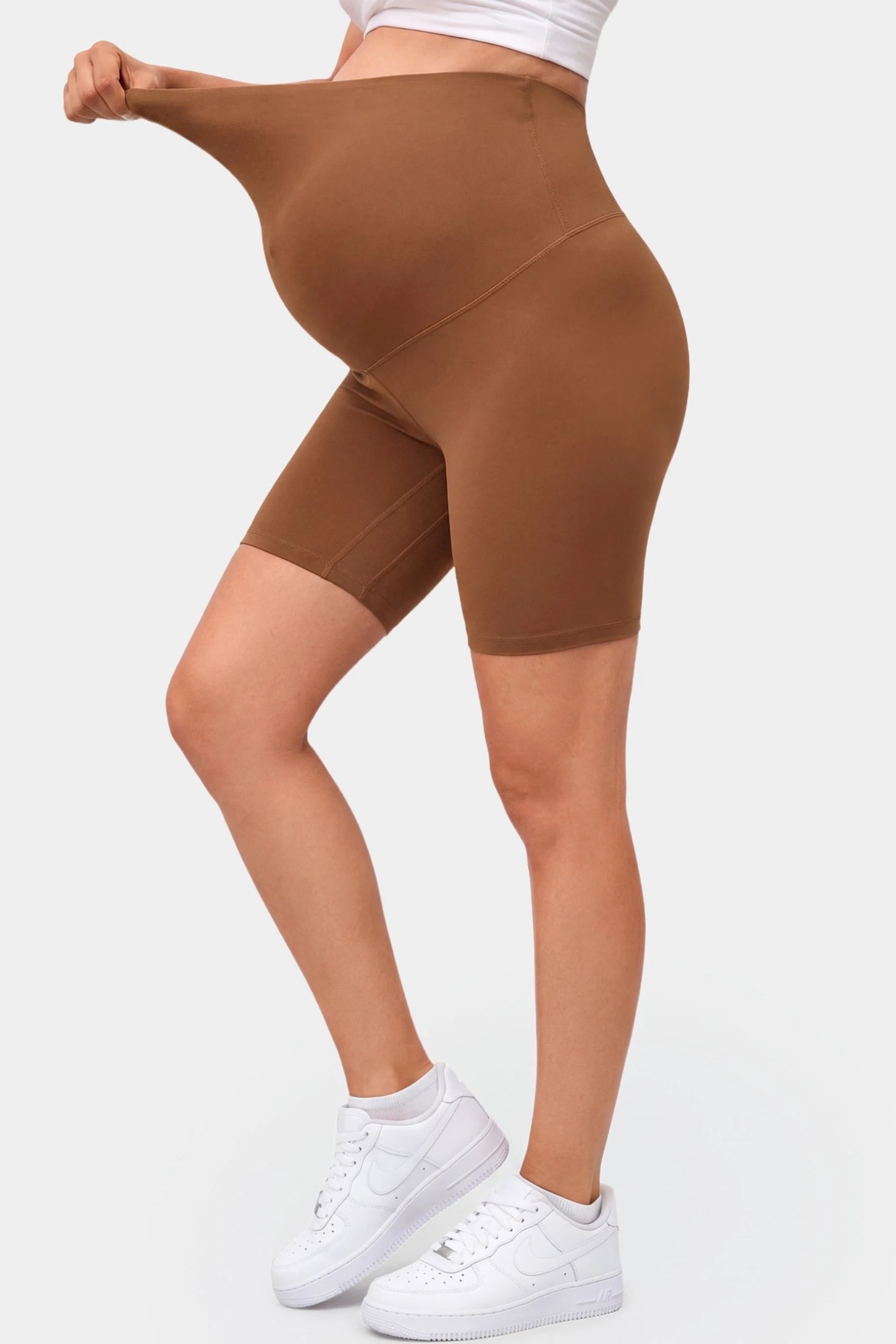 Seamless Belly Support Mid-Thigh Shaping Maternity Shorts Seamless belly support mid-thigh shaping maternity shorts in brown with flexible compression, side view on pregnant model
