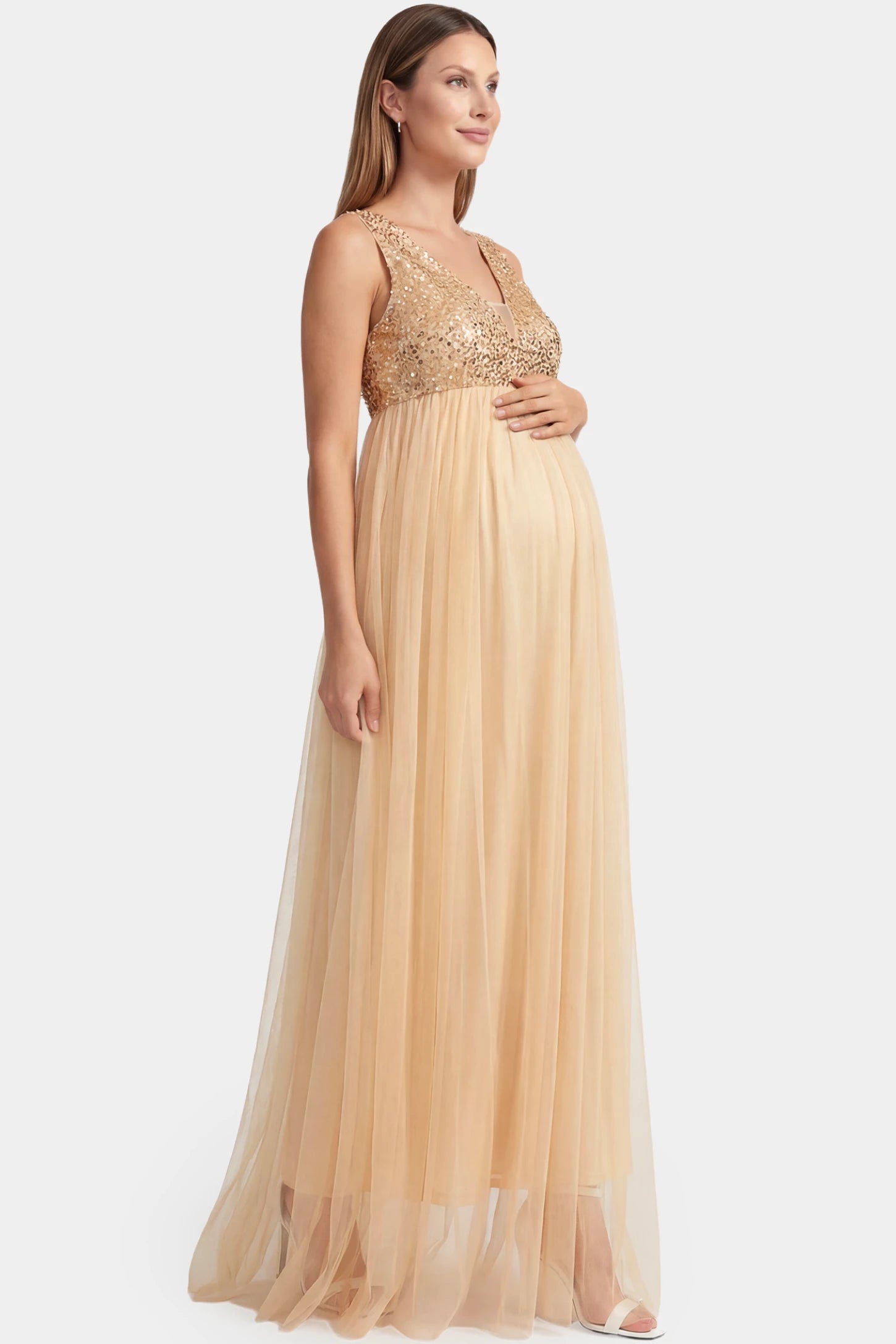 Sequin Bodice Sleeveless Maxi Maternity Dress Sequin bodice sleeveless maxi maternity dress in gold featuring mesh skirt shown in side view on a pregnant model