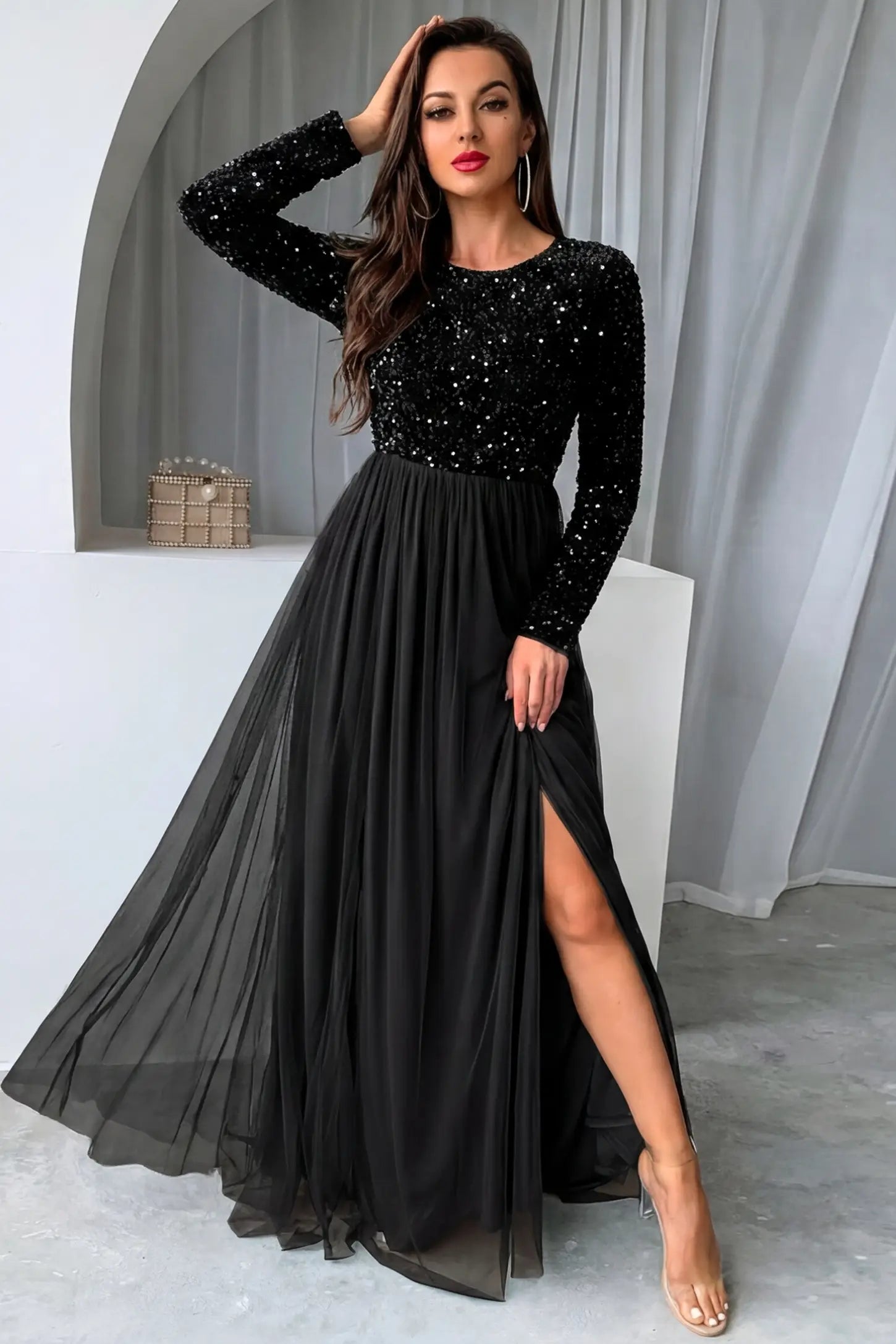 Sequined mesh long sleeve maxi maternity gown in black featuring flowing mesh skirt in full body front view on a editorial lifestyle model