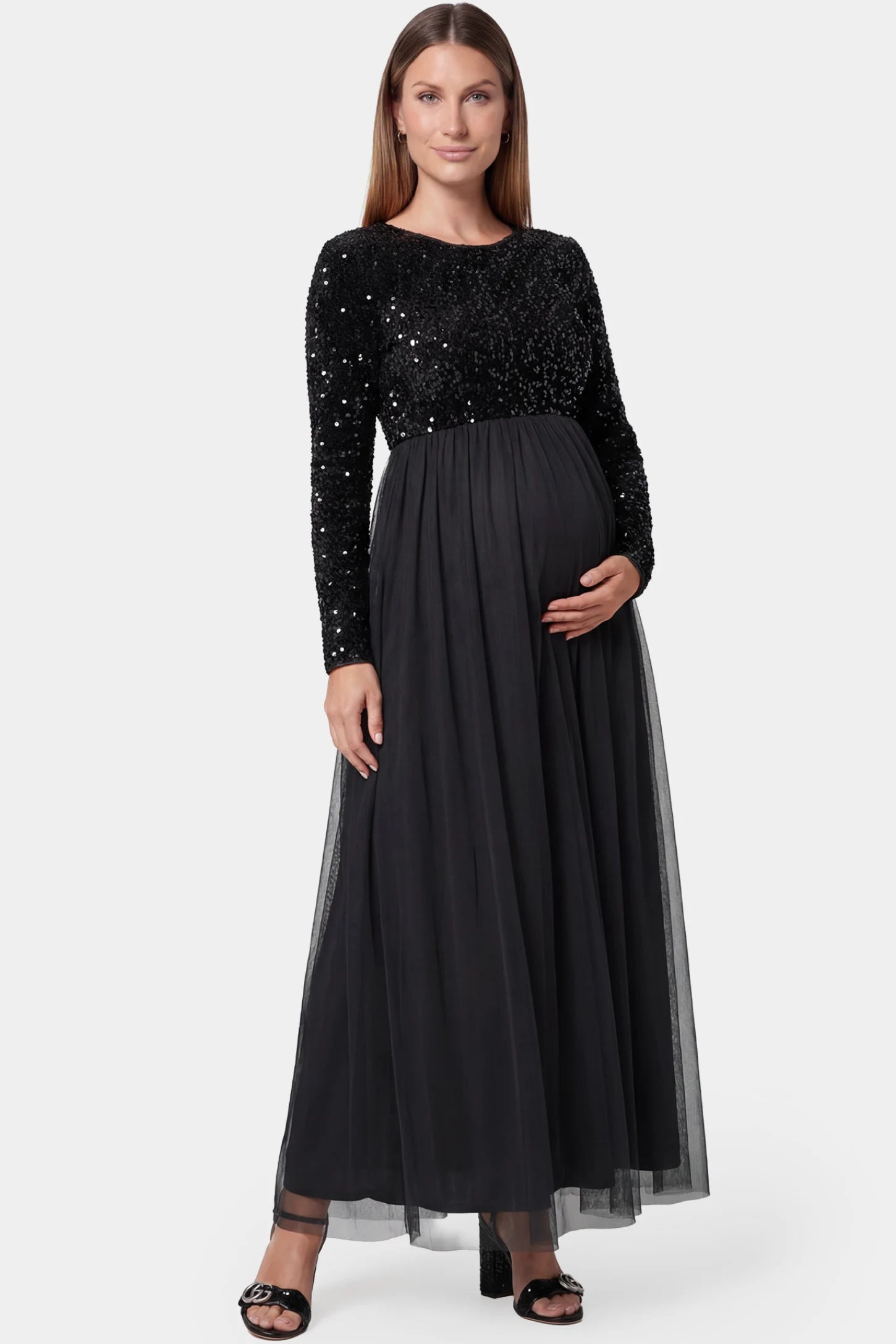 Sequined mesh long sleeve maxi maternity gown in black featuring flowing mesh skirt in full body front view on a pregnant model