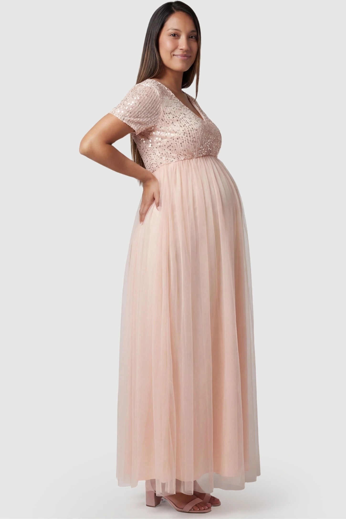 Sequin Ruffle Sleeve Maternity Photoshoot Dress in Pink featuring a flowy tulle skirt on a pregnant model, side view.