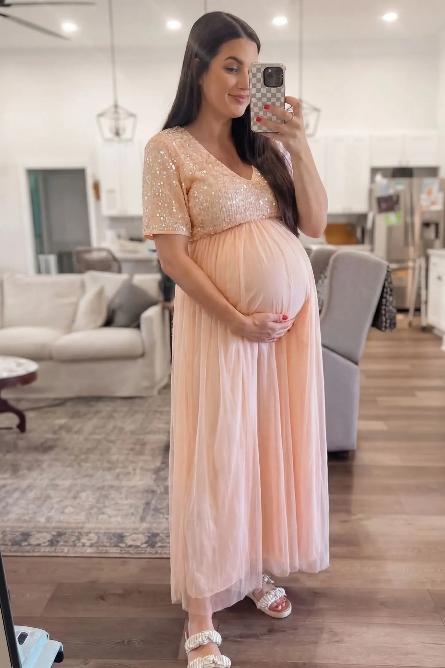 Sequin Ruffle Sleeve Maternity Dress Sequin Ruffle Sleeve Maternity Photoshoot Dress in Pink featuring a flowy tulle skirt on a pregnant model, side view.
