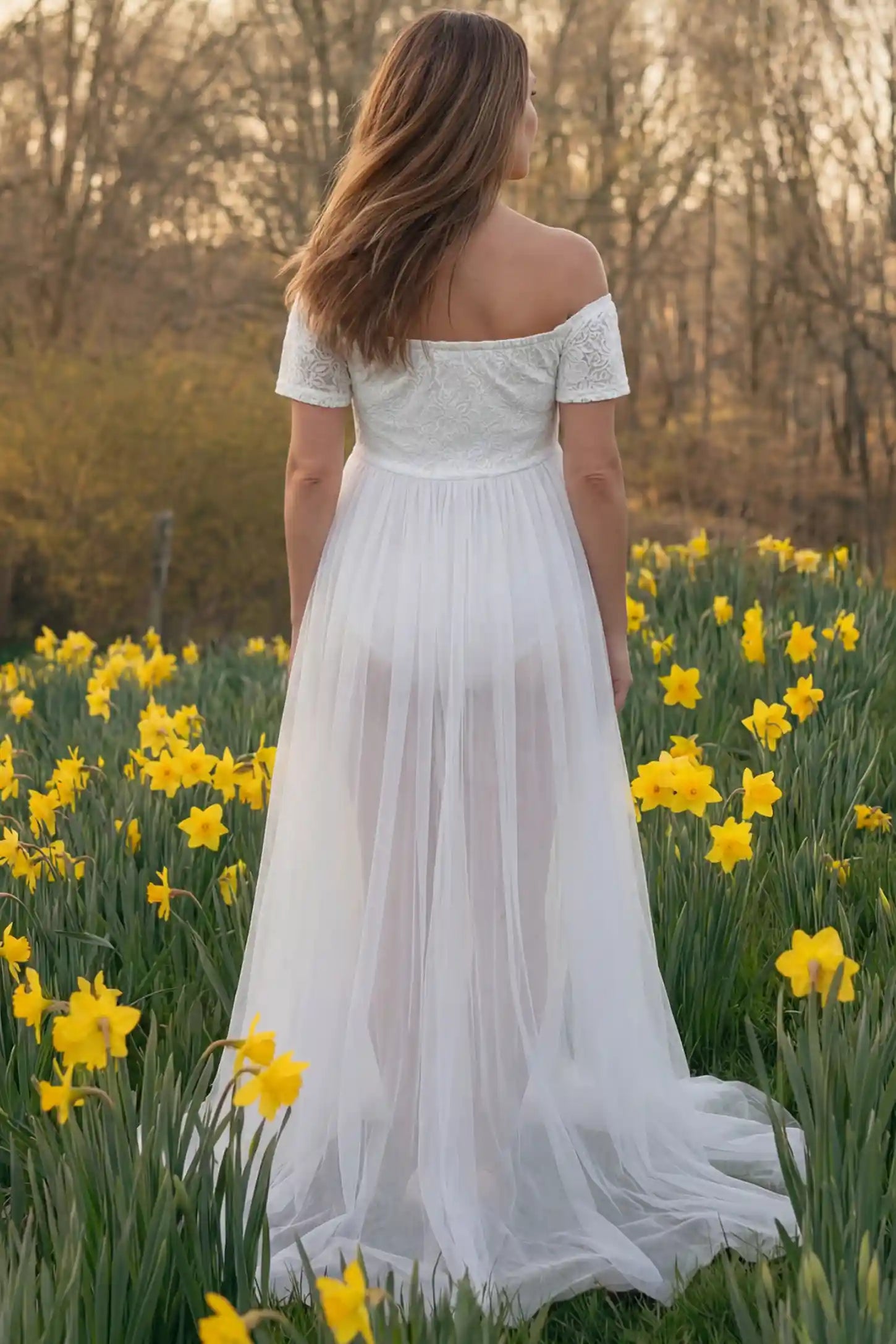 Lace Sheer Overlay Off-Shoulder Maternity Photoshoot Dress Lace Sheer Overlay Off Shoulder Maternity Photoshoot Gown in white featuring flowing sheer skirt on a back view pregnant model.