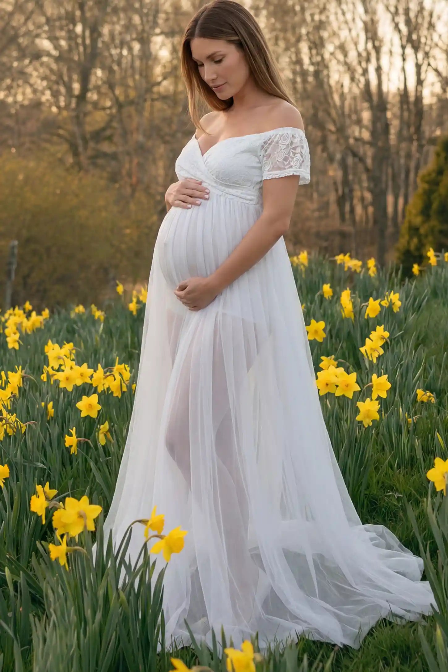 Lace Sheer Overlay Off-Shoulder Maternity Photoshoot Dress Lace Sheer Overlay Off Shoulder Maternity Photoshoot Gown in white featuring sweetheart neckline and flowing sheer skirt on a side view pregnant model.
