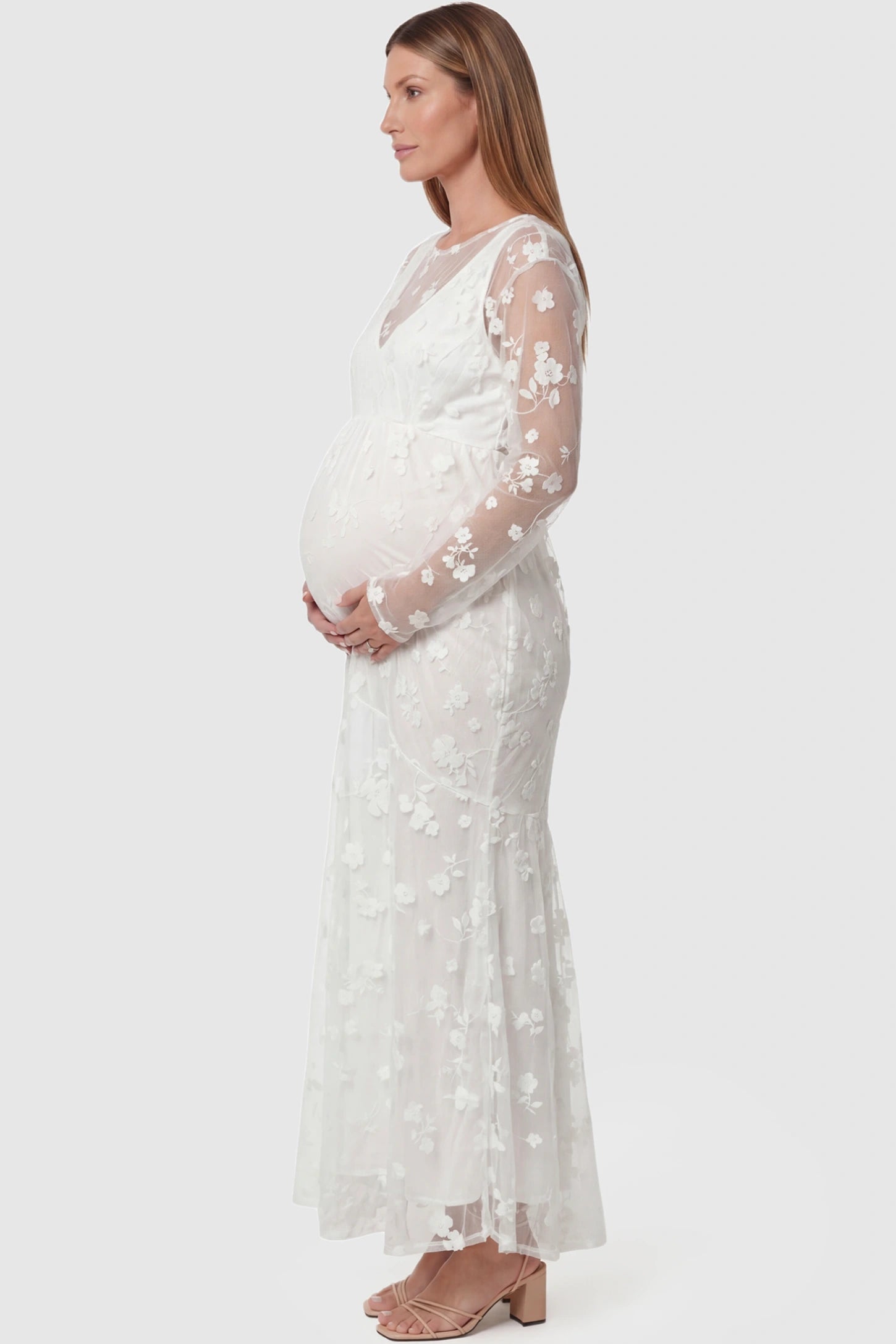 Lace Long Sheer Sleeve Bridal Maternity Gown Lace Long Sheer Sleeve Bridal Maternity Gown in white featuring floral embroidery and long sheer sleeves on a pregnant model side view