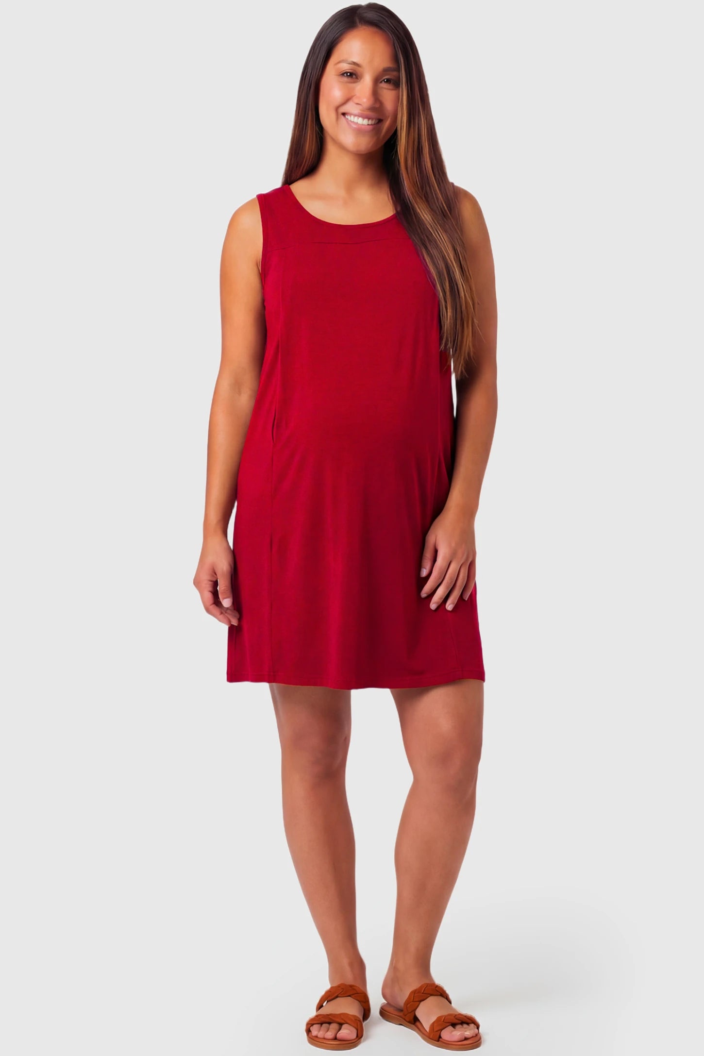 Sleeveless Shift Maternity & Nursing Short Dress in red featuring a relaxed shift silhouette and crew neck on a pregnant model.