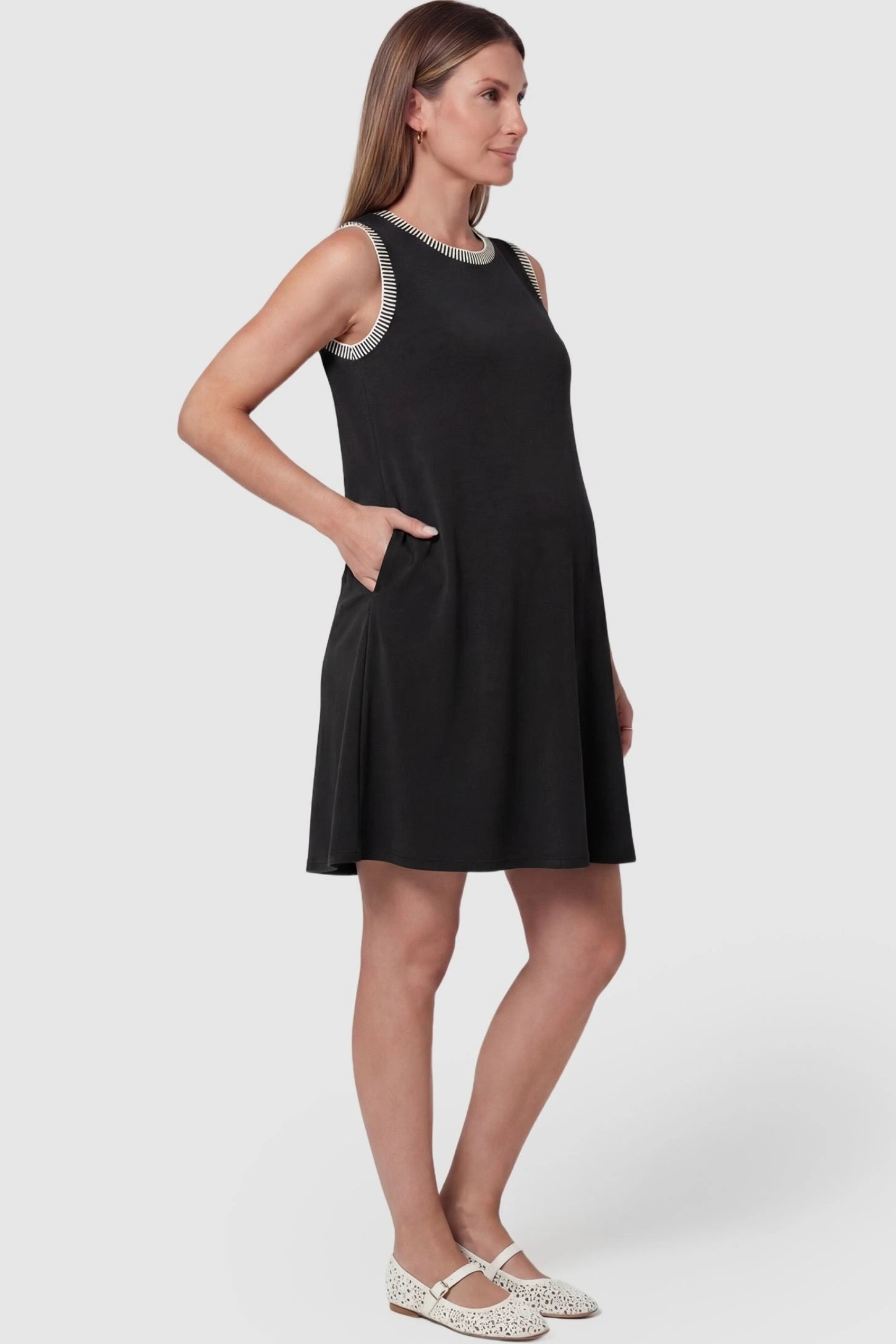 Sleeveless Round Neck A-Line Short Maternity Dress Sleeveless round neck A-line short maternity dress in black featuring functional side pockets in side view on a pregnant model