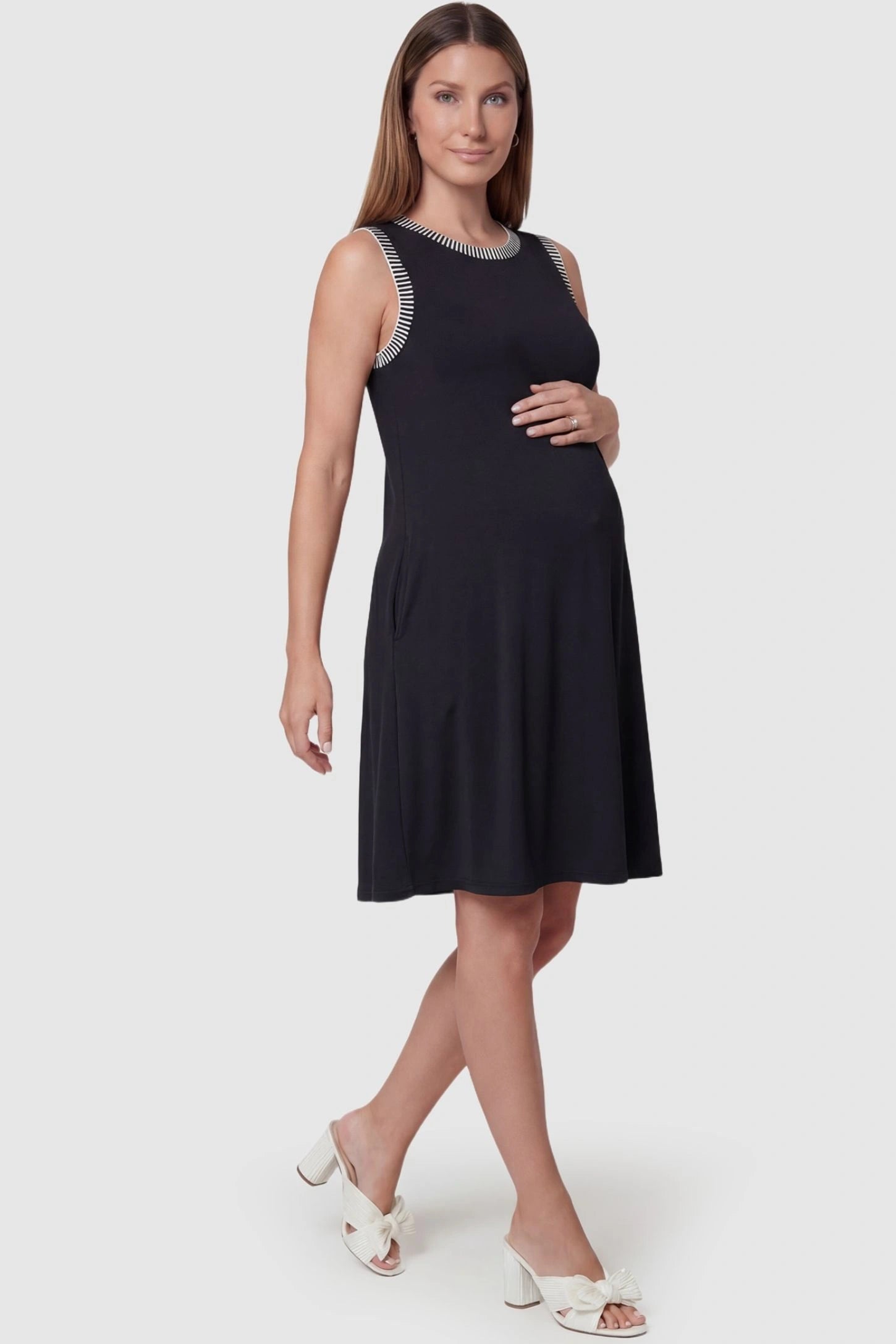 Sleeveless Round Neck A-Line Short Maternity Dress Sleeveless round neck A-line short maternity dress in black featuring umbrella skirt silhouette in full body view on a pregnant model