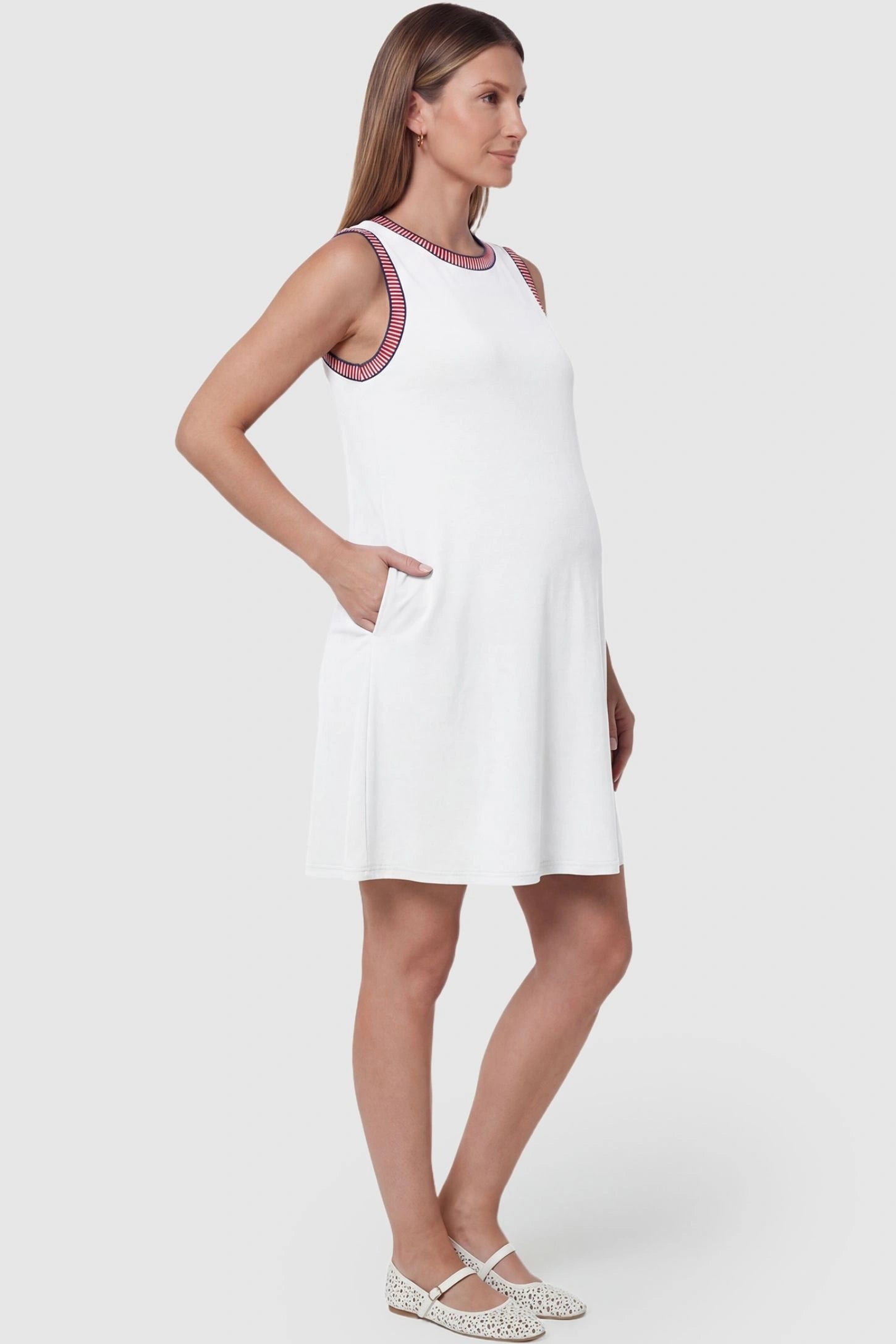 Sleeveless Round Neck A-Line Short Maternity Dress Sleeveless round neck A-line short maternity dress in white featuring functional side pockets in side view on a pregnant model
