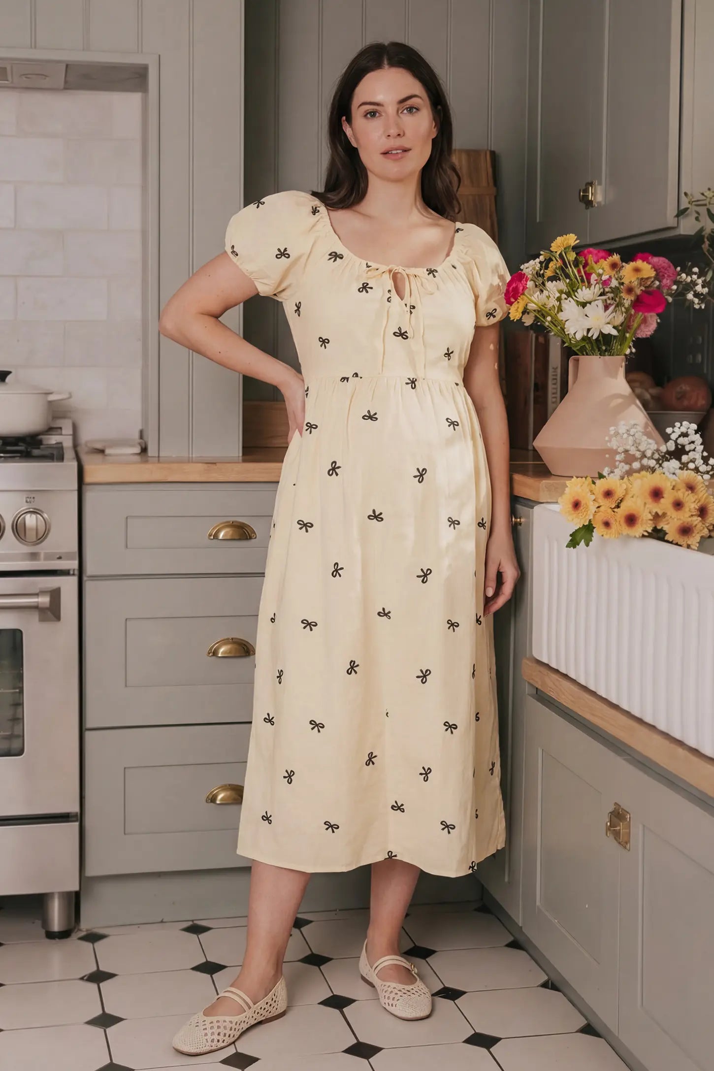 Bow Print Drawstring Neck Maternity Midi Dress Bow print drawstring neck maternity midi dress in beige with drawstring neckline detail, front view on pregnant model