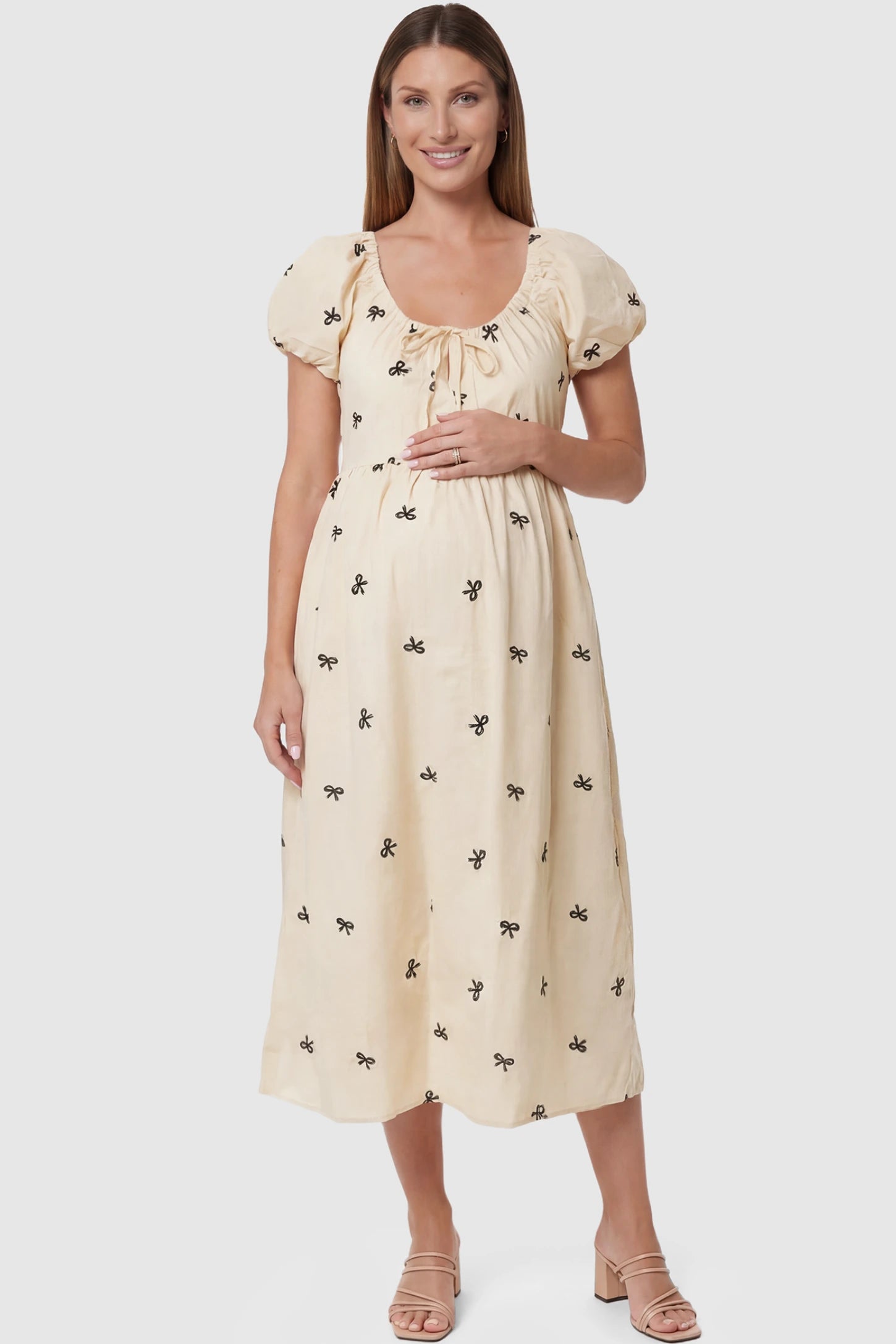 Bow Print Drawstring Neck Maternity Midi Dress Bow print drawstring neck maternity midi dress in beige with drawstring neckline detail, front view on pregnant model