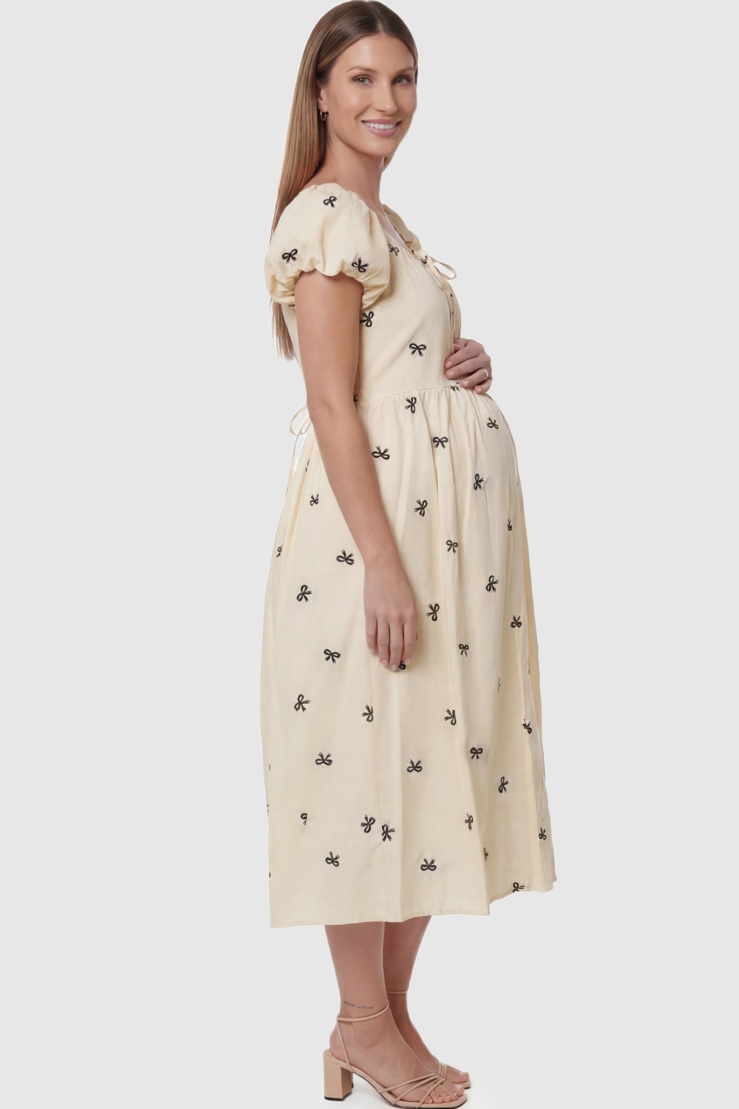 Bow Print Drawstring Neck Maternity Midi Dress Bow print drawstring neck maternity midi dress in beige with short puff sleeve, side view on pregnant model