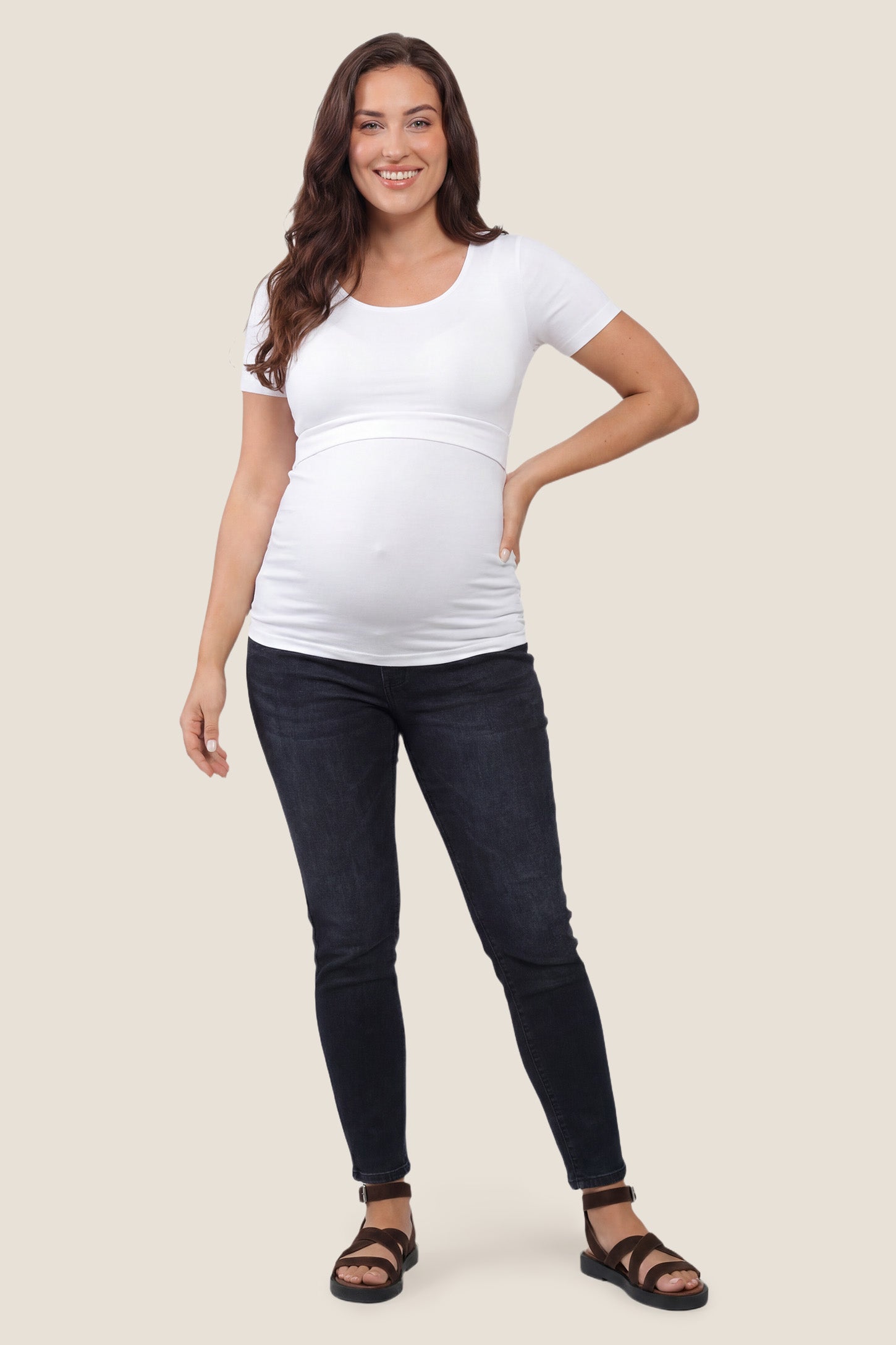 Basic Crew Neck Maternity & Nursing T-Shirt Basic Crew Neck Maternity & Nursing T-Shirt in White featuring a stretch-fit round neck design on a pregnant model, full body shot.