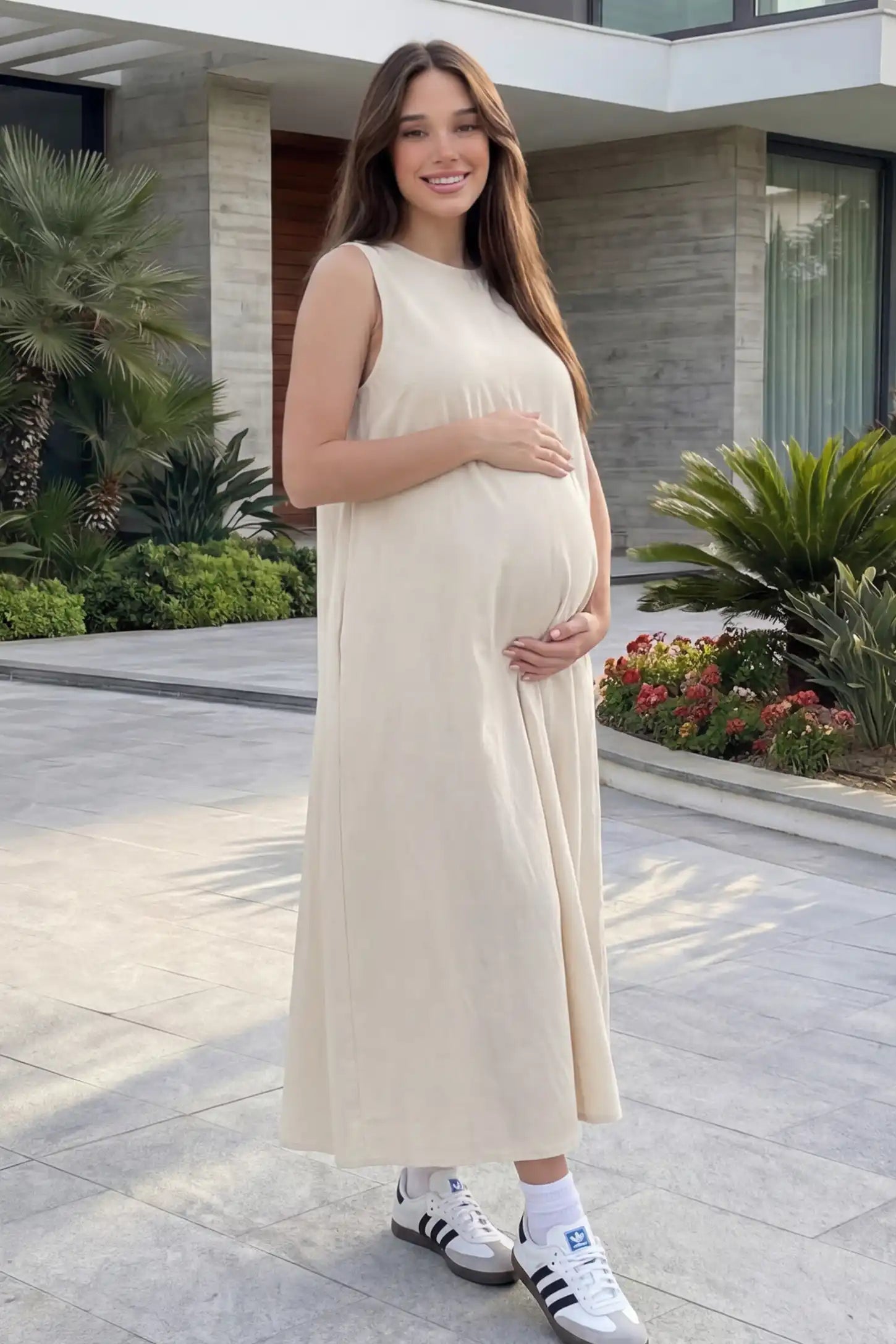 Sleeveless Pocketed Longline Hem Maternity Midi Dress Sleeveless pocketed longline hem maternity midi dress in cream with sleeveless design and longline hem, front view on pregnant model