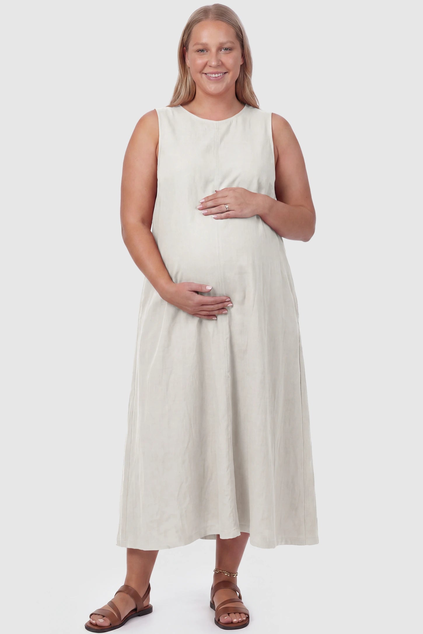 Sleeveless Pocketed Longline Hem Maternity Midi Dress Sleeveless pocketed longline hem maternity midi dress in cream with sleeveless design and longline hem, front view on plus-size model