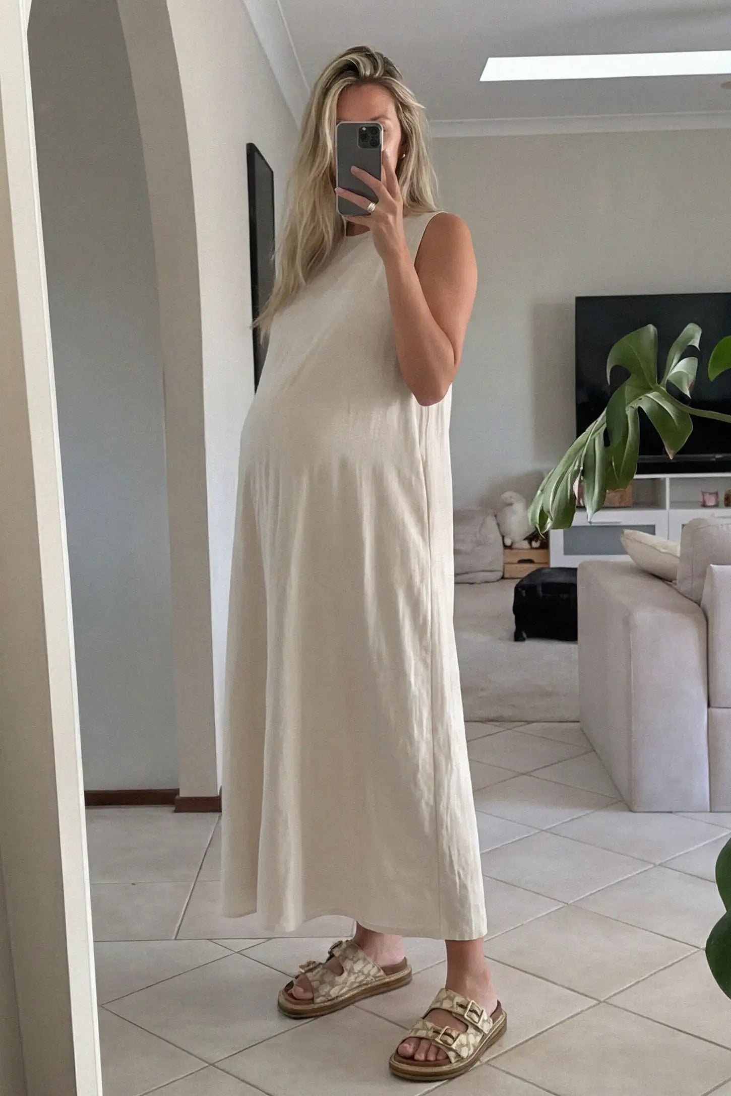 Sleeveless Pocketed Longline Hem Maternity Midi Dress Sleeveless pocketed longline hem maternity midi dress in cream with sleeveless design and longline hem, front view on pregnant model